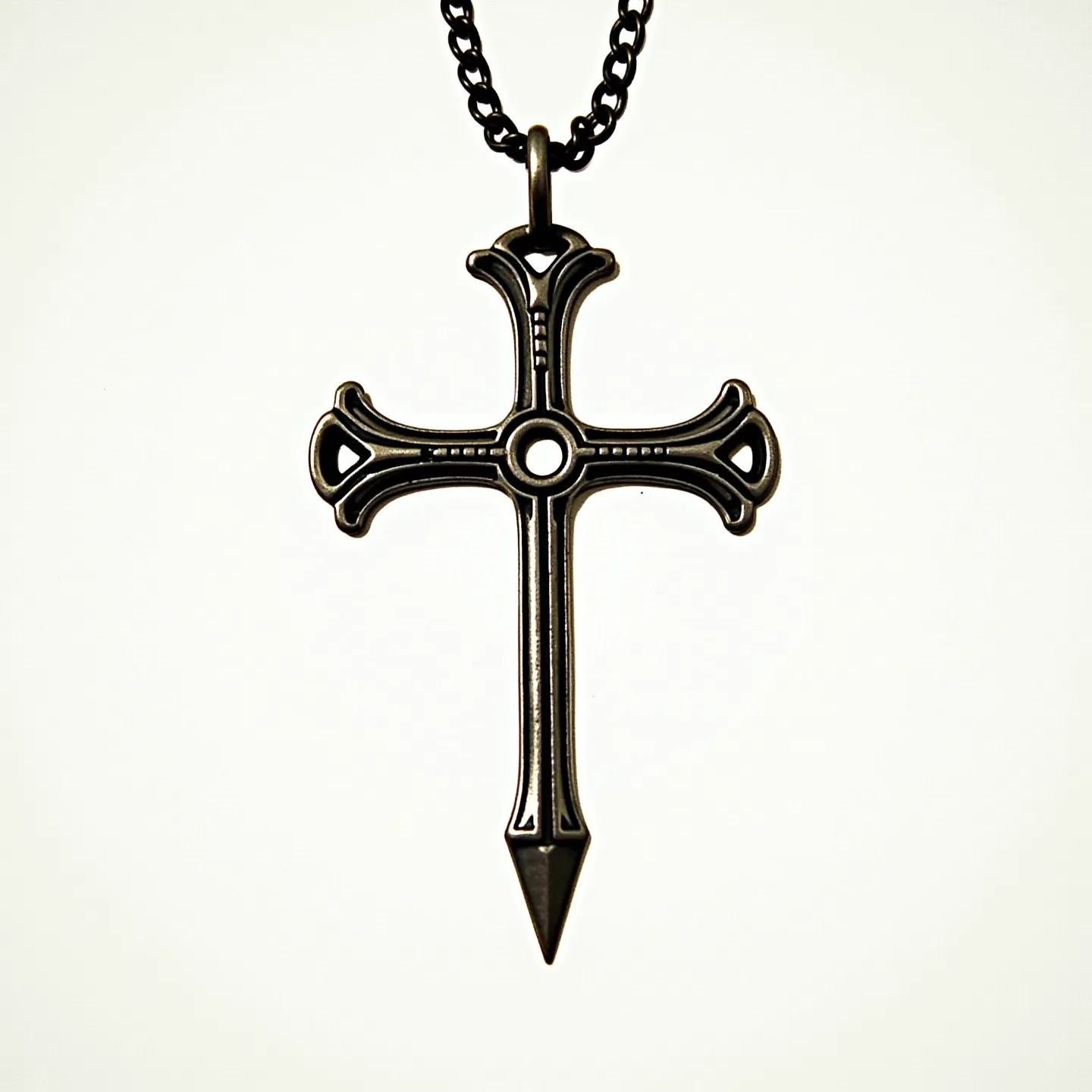 This nail cross necklace features a striking design resembling hand-forged nails forming a cross. The pendant appears to be made of a dark, metallic material, possibly stainless steel or a metal alloy, with a polished finish that gives it a subtle sheen. The intersecting nails create a central circular motif, adding to the intricate craftsmanship. The pendant hangs from a robust link chain, which complements its rustic aesthetic. The necklace likely includes a standard clasp, such as a lobster clasp, ensuring secure attachment and ease of wear.