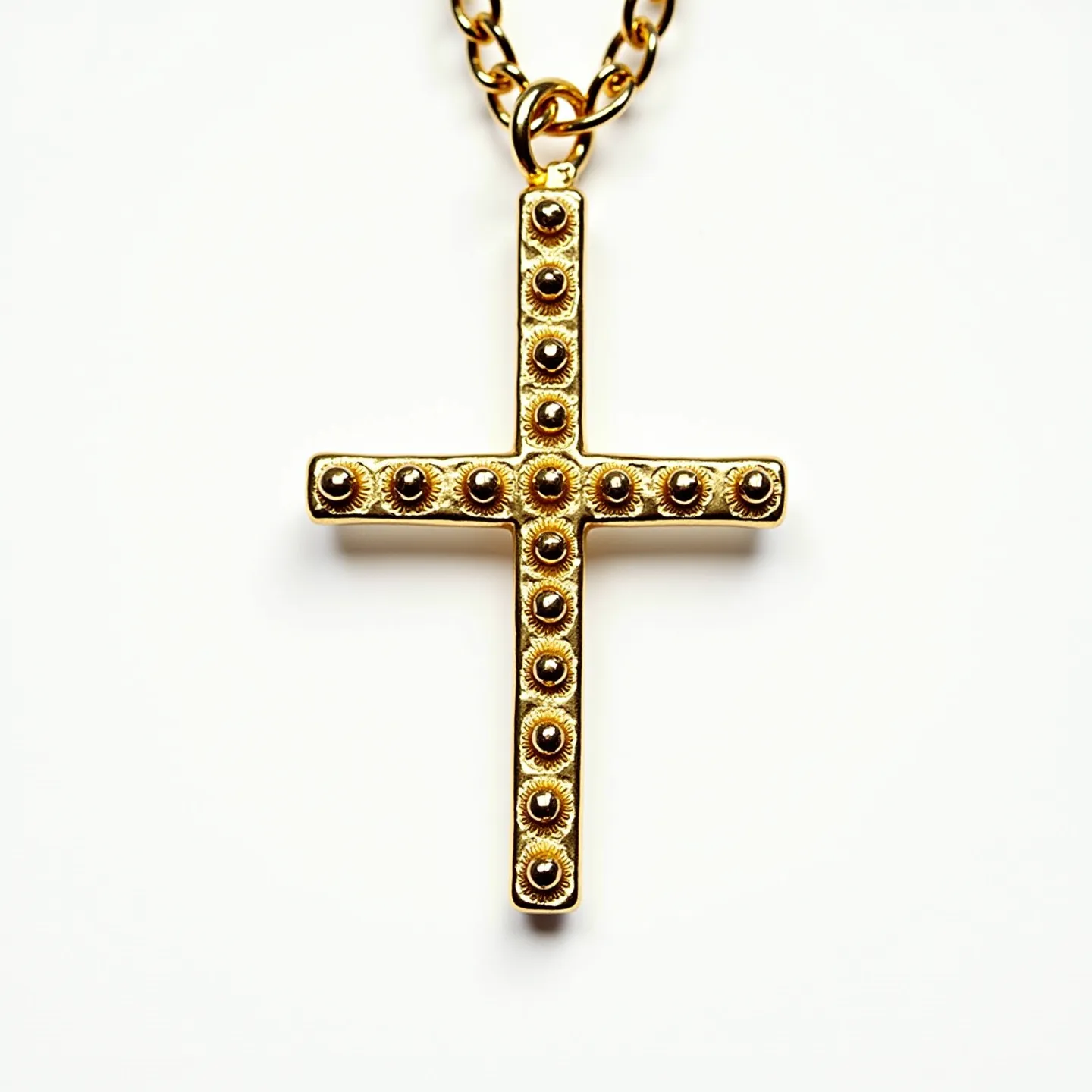 This nail cross necklace is crafted from a gold-toned material, featuring a rugged, industrial design. The cross is embellished with circular rivet-like details, giving the appearance of nails driven into the structure. Each "nail" is not adorned with stones or gems, maintaining a uniform metallic finish throughout. The cross pendant is suspended from a chunky gold-toned chain, which is likely attached with a sturdy clasp designed for durability. The overall design combines a sense of ruggedness and elegance, making it a bold statement piece.