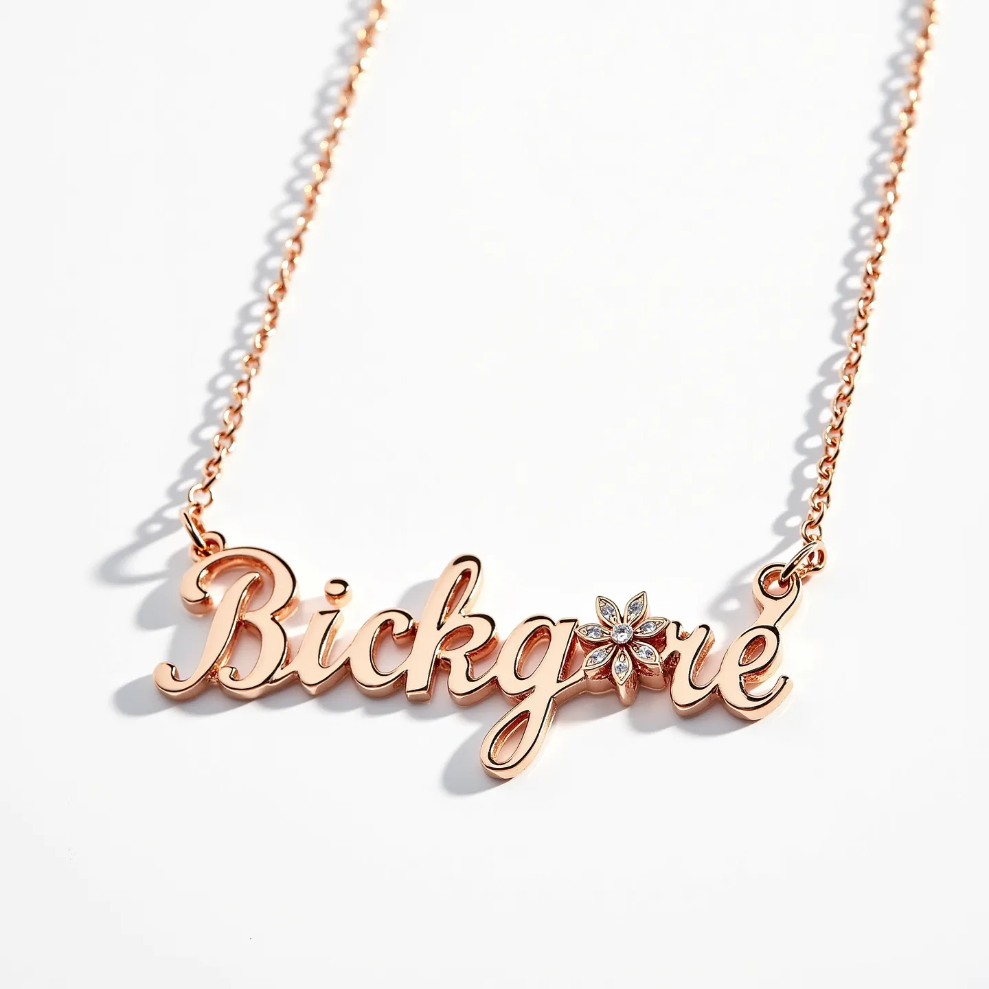 This name chain necklace features a stylish script design crafted from a lustrous rose gold material. The pendant highlights a charming floral motif adorned with small, round-cut diamonds, elegantly set in a pavé style, providing a delicate sparkle. The fine links of the chain complement the intricate detail of the name, adding a touch of elegance. The connection between the chain and the pendant is seamless, enhancing the unified aesthetic of the piece. This necklace is fastened with a secure clasp that ensures ease of wear while maintaining its sophisticated appearance.