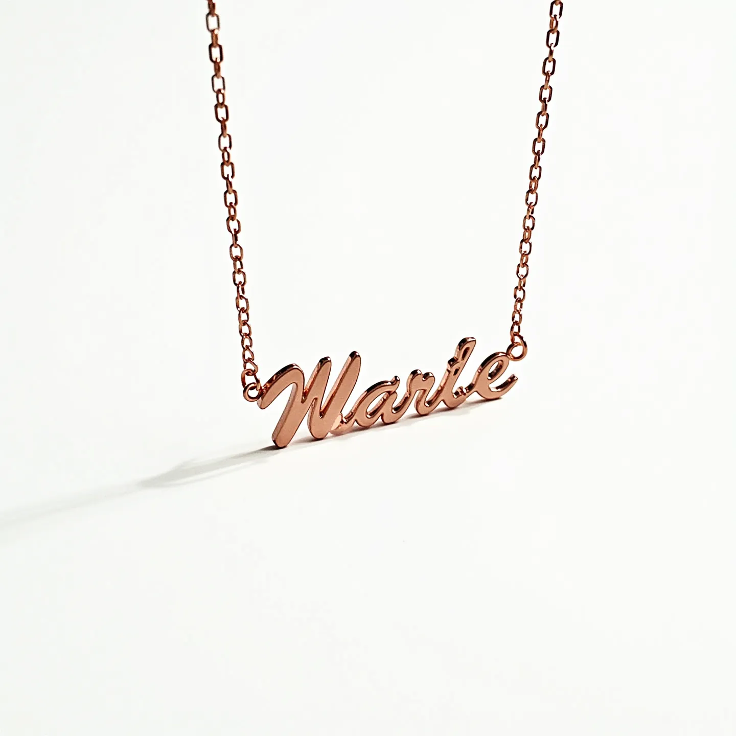 This name chain necklace features a cursive script design where the name "Marie" is elegantly crafted as the main pendant. The piece is made from a shiny rose gold material, giving it a sophisticated and warm hue. The name is seamlessly integrated into the chain, which consists of delicate yet sturdy links that provide a refined and feminine look. The clasp or attachment is not visible, but the overall construction suggests easy wearability and secure closure. The necklace’s simplicity and elegance make it suitable for various occasions.