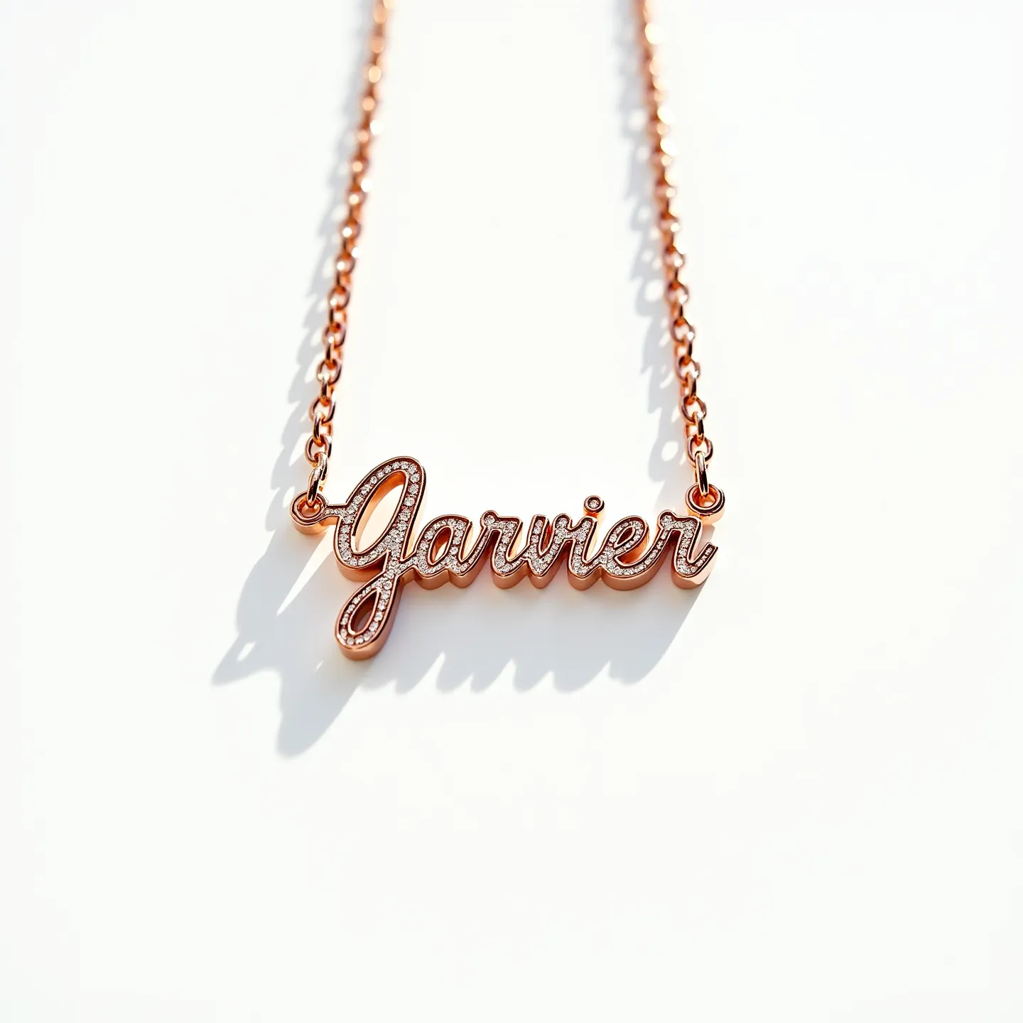 This name chain necklace features a cursive script nameplate crafted from rose gold-toned metal, giving it an elegant and sophisticated appearance. The nameplate is accented with small round clear stones, likely cubic zirconia or diamonds, set into the surface, adding a touch of sparkle and refinement. The stones are meticulously positioned along the top edge of each letter within the name, providing a subtle yet striking contrast with the warm hue of the metal. The chain is a simple link chain that complements the nameplate, offering a continuous, cohesive aesthetic. The necklace is equipped with a standard spring ring clasp, ensuring secure and easy fastening for everyday wear.