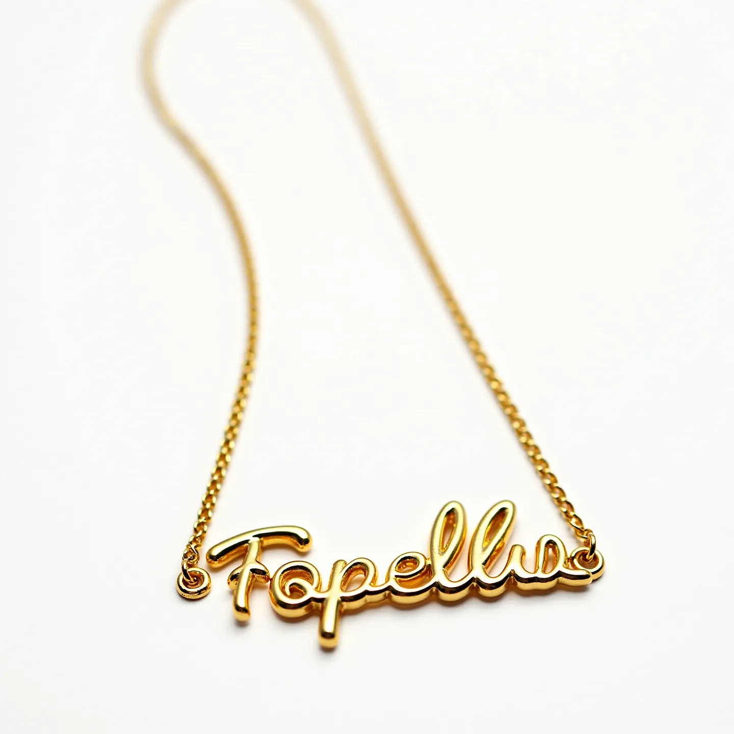 This name chain necklace features the word "Fopellu" crafted from a polished gold-tone metal, forming an elegant and flowing script. The chain is composed of a slender and uniform link style that complements the delicate appearance of the nameplate. The nameplate seamlessly integrates with the chain through small loops on either end, offering a cohesive and continuous design. The simplicity of the necklace enhances its versatility, making it suitable for various occasions. The shiny finish of the metal lends a sophisticated touch to the overall aesthetic.