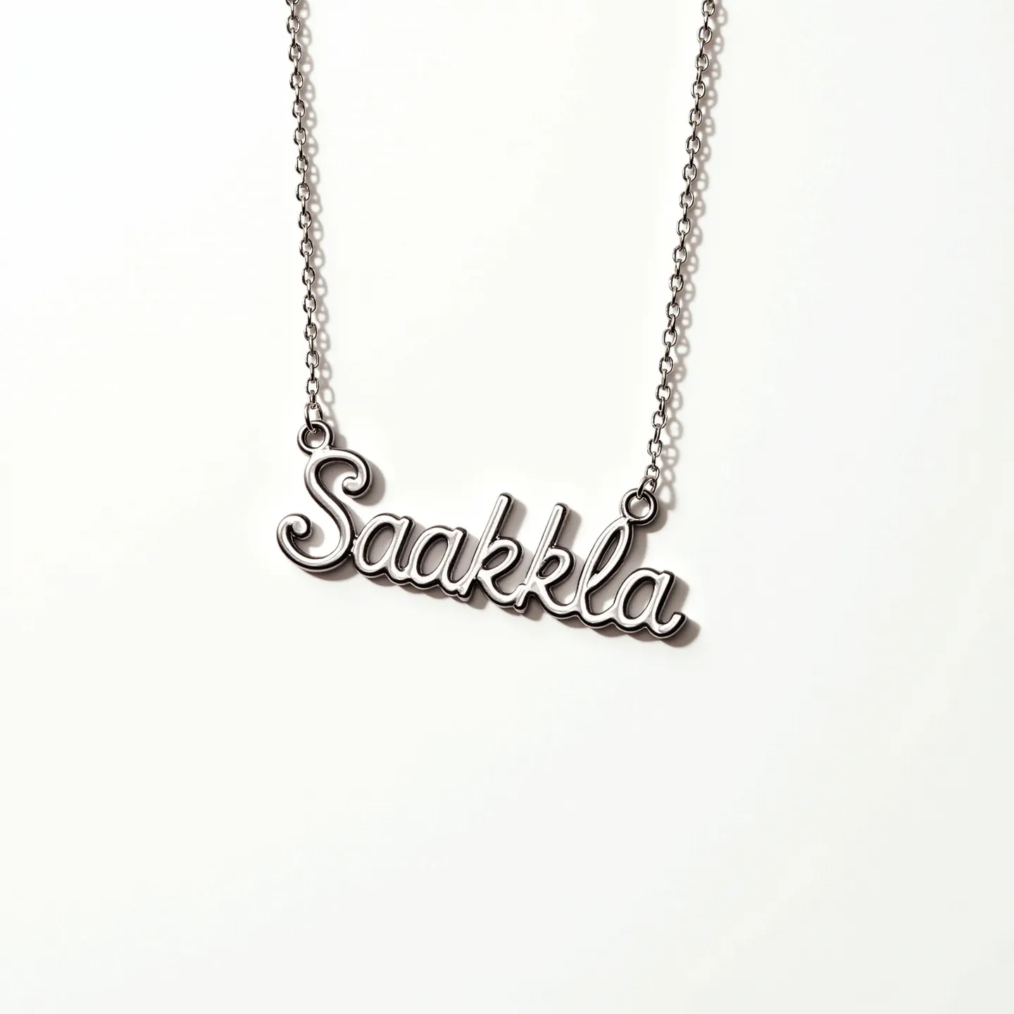 This name necklace features the name "Saakkla" elegantly rendered in a sleek script, crafted from a shiny metal that resembles silver. The necklace connects to a delicate chain on either side of the name, indicating small loop attachments at the beginning and end of the inscription. The chain appears to be a cable link style, contributing to a minimalist and refined appearance. There are no visible gems or stones embedded in the design, giving it a clean and modern aesthetic. The necklace likely features a simple clasp mechanism, typical of such designs, ensuring easy wearability and security around the neck.