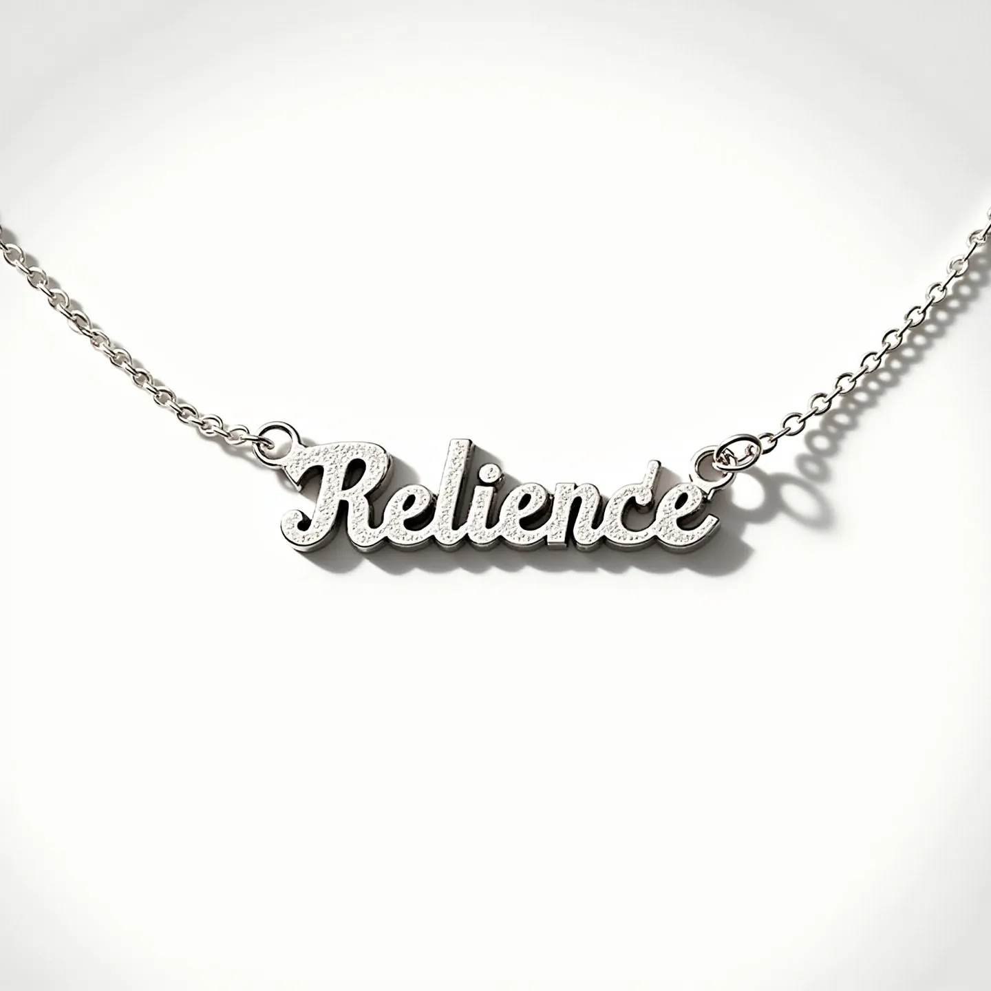 This name necklace features the word "Relience" crafted in a cursive script, likely made from a high-quality metal such as silver or white gold, giving it a sleek and polished appearance. The surface of the letters has a texture that creates a distinctive shine, suggesting a modern and elegant design. Each end of the nameplate seamlessly attaches to a delicate chain using small, circular loops. The necklace is secured with a subtle clasp, ensuring both security and comfort for the wearer. The overall design is minimalistic yet stylish, making it suitable for everyday wear or special occasions.