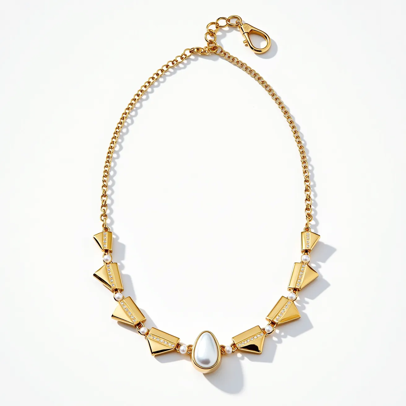 This pearl necklace features a sophisticated design combining gold-toned metal with small pearl accents interspersed between sleek, geometric gold elements. The central piece is a teardrop-shaped white stone with a glossy finish, likely a simulated pearl or gemstone, set in a gold bezel setting. The necklace is connected by a series of gold chain links that extend to a lobster clasp for secure fastening. The overall design blends modern elegance with a touch of classic style, highlighted by the meticulous arrangement and combination of materials and shapes.