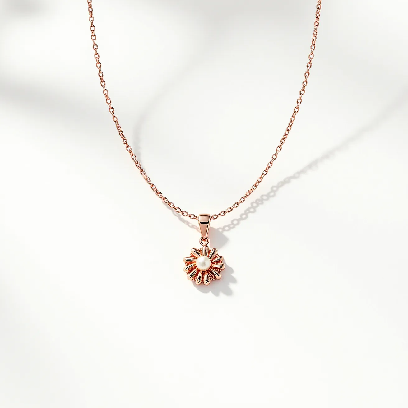 This pearl necklace features a delicate chain made from a rose gold material, adding a subtle, warm elegance to the piece. The centerpiece of the necklace is a pendant with a small, round pearl set at its heart. The pearl is surrounded by a floral-inspired design, crafted from rose gold metal that forms petal-like shapes around it. The pearl is set in a minimalist manner that enhances its natural luster without overpowering it. The chain appears to be secured with a standard clasp, ensuring ease of wear while maintaining the necklace’s refined aesthetic.