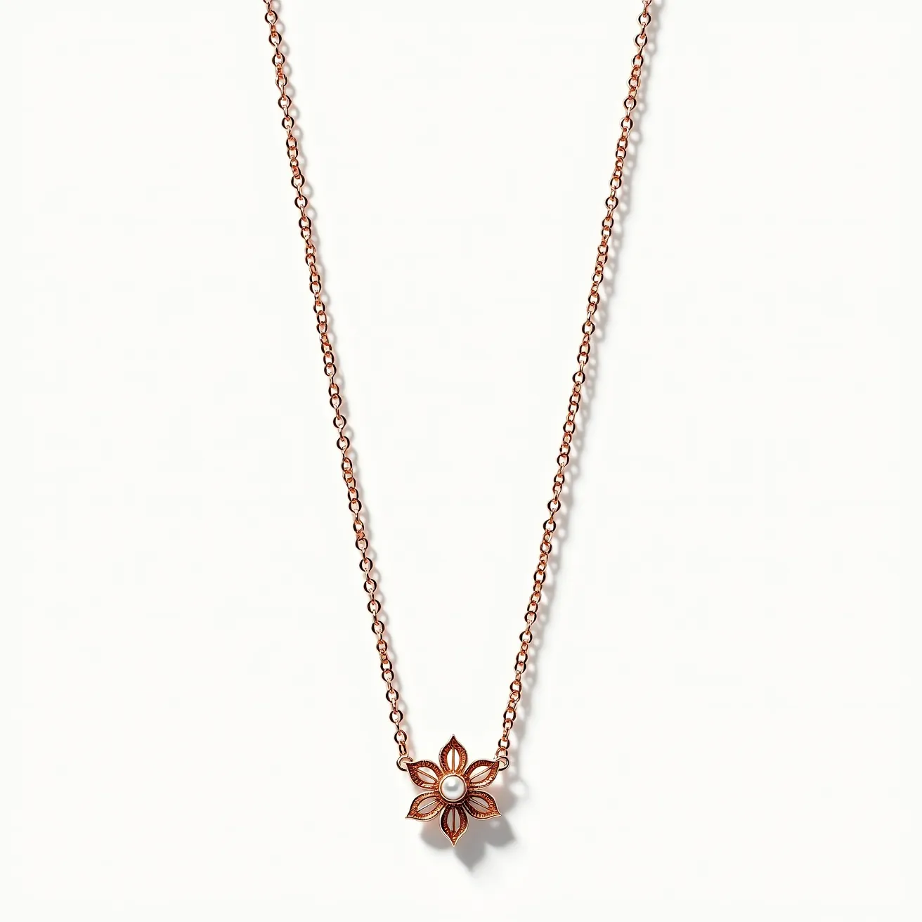 This pearl necklace features a delicate chain crafted from a warm, rose-gold-toned metal. At its center is a floral pendant design with a single small pearl set as its focal point. The pearl is surrounded by a flower pattern with detailed metalwork, showcasing a stylized and symmetrical six-petal design. The pearl is smooth and shiny, sitting securely in a bezel setting. The chain links are small and uniform, complementing the intricate floral design without being distracting. The mechanism of the clasp is not visible, but the overall design suggests an elegant and refined piece.