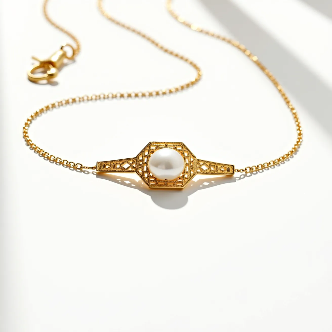 This pearl necklace features a single, round pearl encased in a gold setting that is intricately designed with geometric patterns. The setting includes fine details surrounding the pearl, showcasing an elegant craftsmanship that highlights the central gem. The necklace is made of a delicate gold chain, complementing the gold setting of the pearl. It is secured with a gold lobster clasp, ensuring both style and functionality. The combination of the smooth pearl and the ornate gold design creates a sophisticated and timeless piece of jewelry.