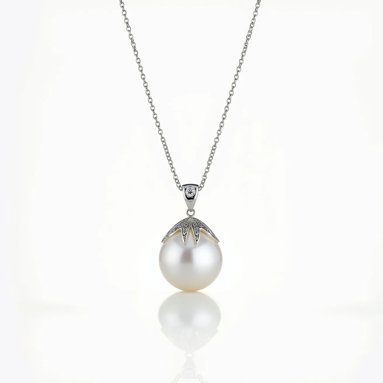 This pearl necklace features a single lustrous pearl as its centerpiece, suspended from a delicate chain. The pearl is adorned with an elegant silver cap embellished with small sparkling stones, likely diamonds, set in a pavé style that accentuates its brilliance. The chain appears to be crafted from a fine metal, possibly sterling silver or white gold, offering a sleek and sophisticated finish. The pendant attachment is smoothly integrated, ensuring the pearl hangs gracefully. The clasp of the necklace is subtle and likely designed for ease of use, enhancing the overall elegance of the piece.