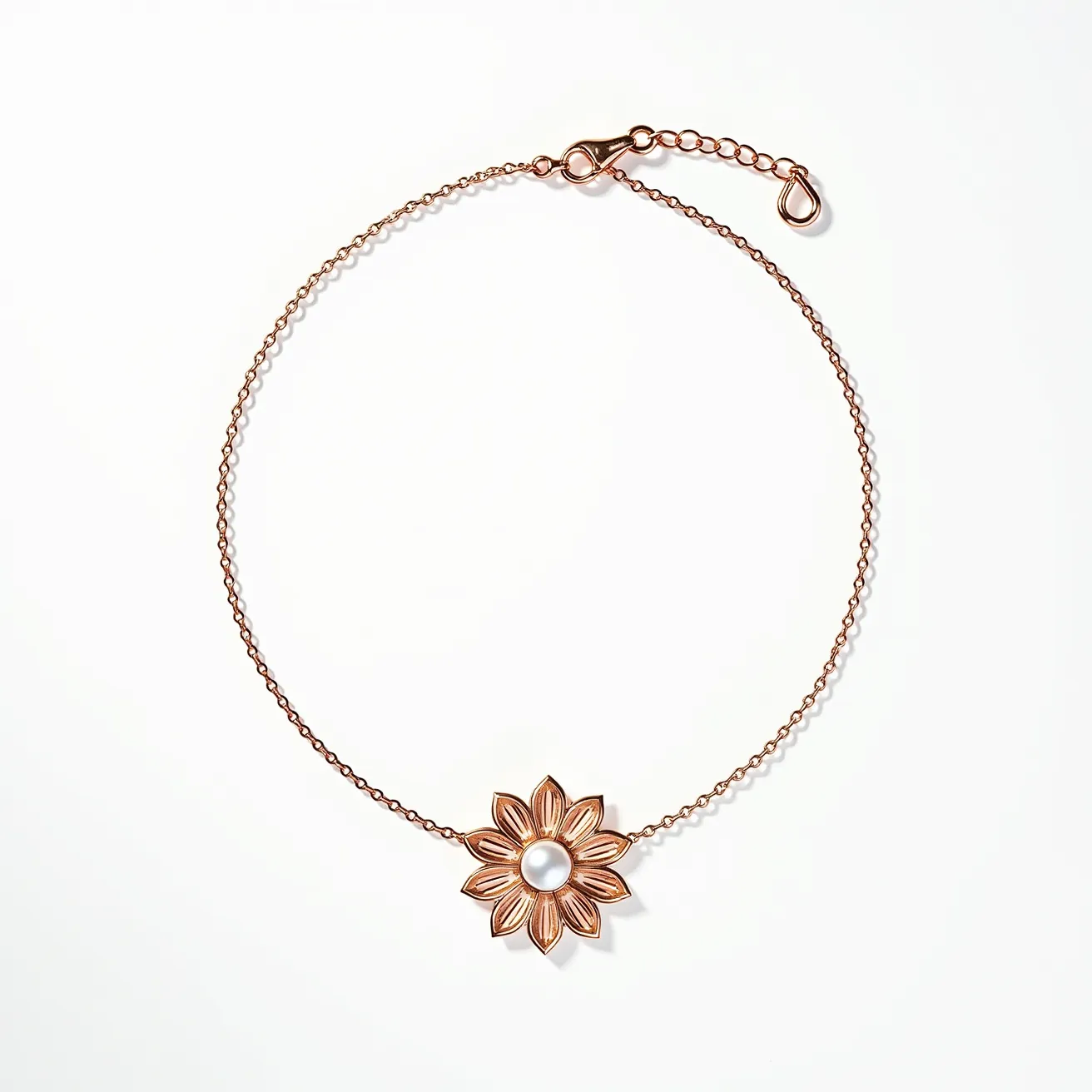 This necklace features a delicate chain crafted from a metal with a rose-gold finish, showcasing a central pendant in the shape of a flower. The flower pendant is designed with intricately detailed petals and highlights a single round pearl set at its center, adding an elegant and classic touch. The necklace is secured with a lobster clasp, which is accompanied by an adjustable chain extension, allowing for versatile length adjustments. The combination of the floral motif and the pearl element gives the piece a refined and timeless aesthetic.