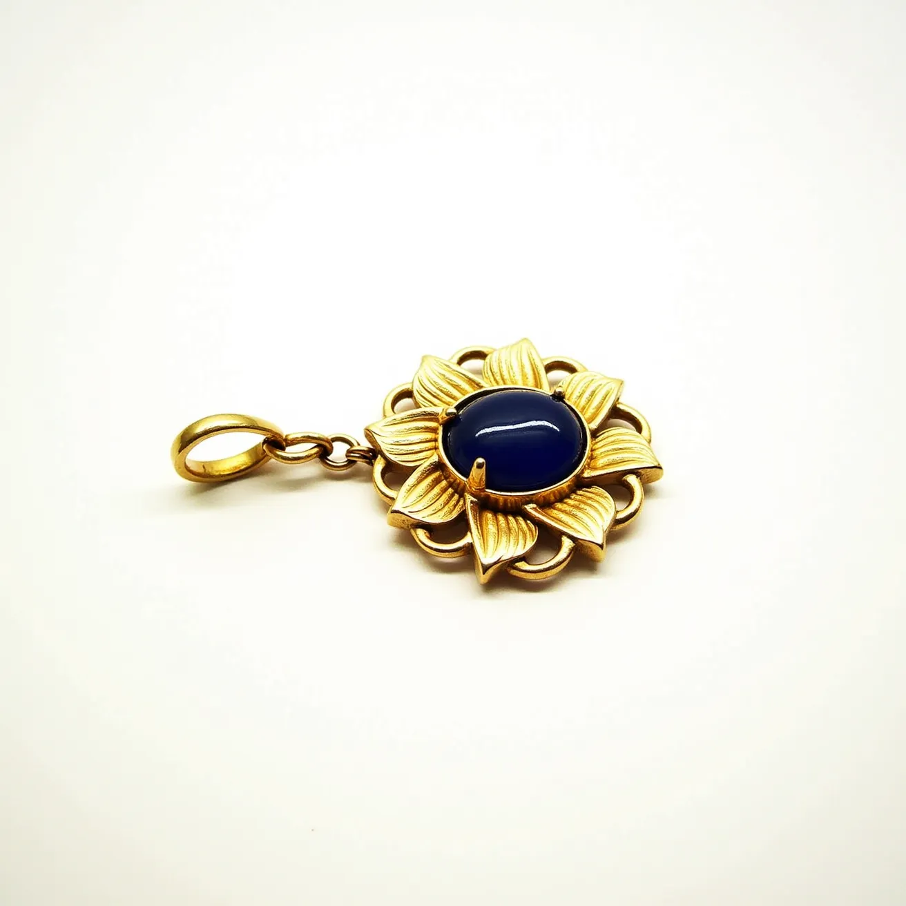 This statement pendant features a striking design with a central dark blue cabochon stone. The stone is set in a bezel setting and surrounded by a petal-like motif, crafted from a gold-toned metal that gives the pendant an elegant floral appearance. The petals are detailed with fine lines, adding texture and depth to the piece. The pendant is attached to a simple loop clasp, making it easy to attach to a chain or necklace. Its combination of rich materials and thoughtful detailing makes it a bold and stylish accessory.