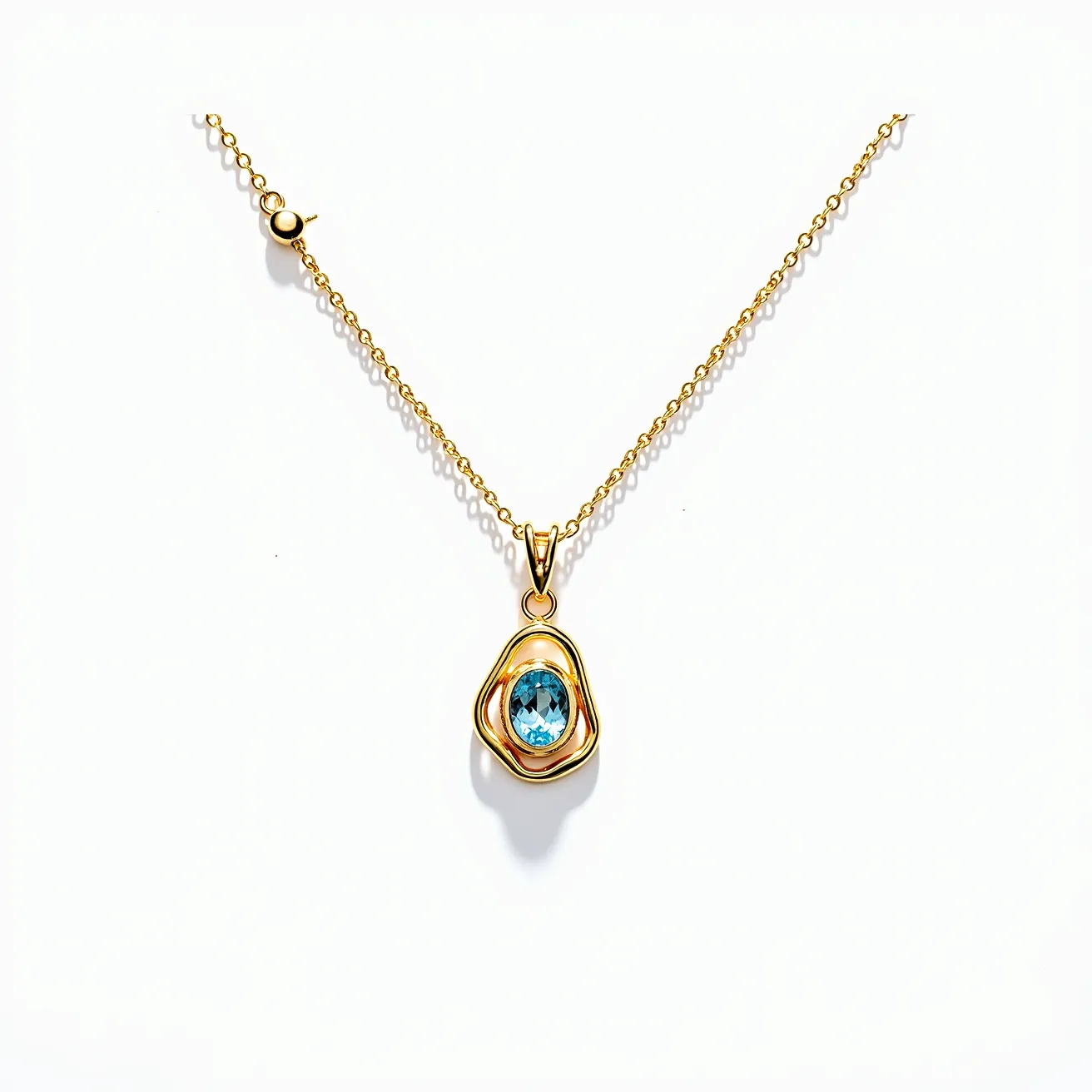 This statement pendant features a striking design with a yellow gold setting that elegantly frames an oval-cut blue gemstone, likely blue topaz. The stone is securely encased within a smooth, bezel setting that enhances its vibrant color and brilliance. The pendant is suspended from a fine gold chain, connected by a sleek V-shaped bail. The chain includes an adjustable section with a small gold ball slider, providing versatility in length, and is secured with a lobster claw clasp for easy wear. The overall design exudes a modern elegance, making it a captivating accessory.