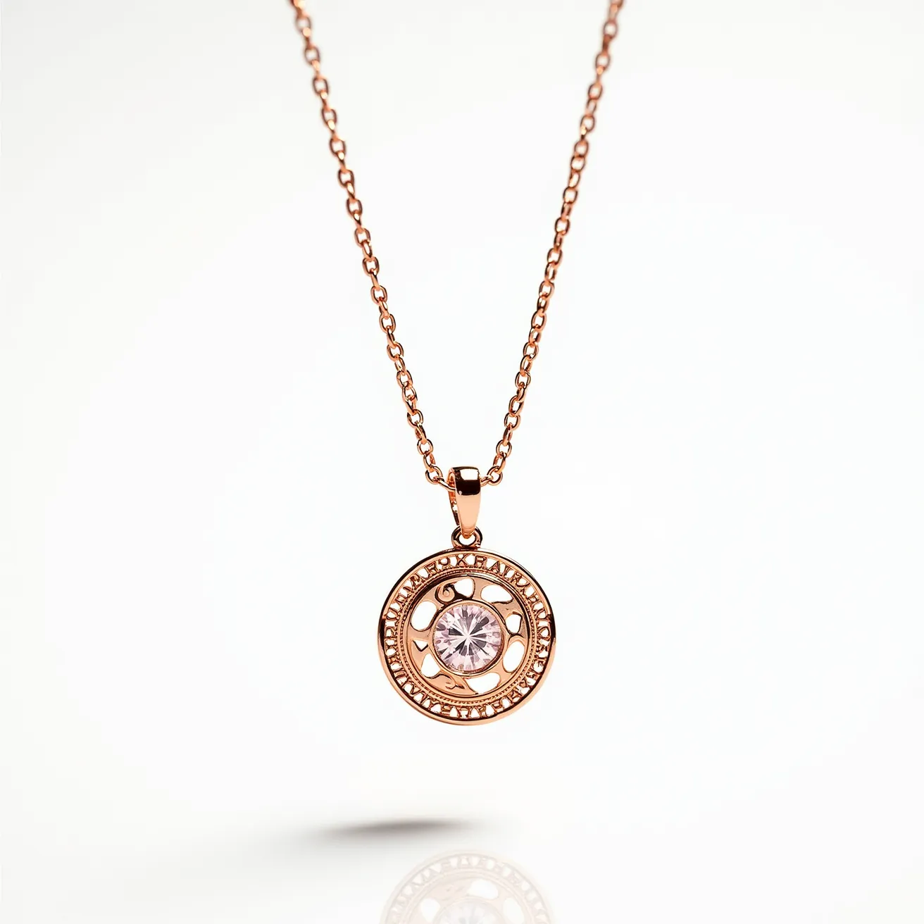 This pendant necklace features a circular design with a prominent gemstone at its center, likely a round-cut diamond or cubic zirconia, set in a bezel setting. The pendant is crafted from a rose gold-toned metal, adding a warm hue to the overall design. Surrounding the central stone is an intricate, openwork pattern with engraved text, contributing to its unique style. The chain, also rose gold-toned, has a delicate and fine link design that complements the pendant. The necklace is equipped with a standard lobster clasp, ensuring secure and adjustable wear.