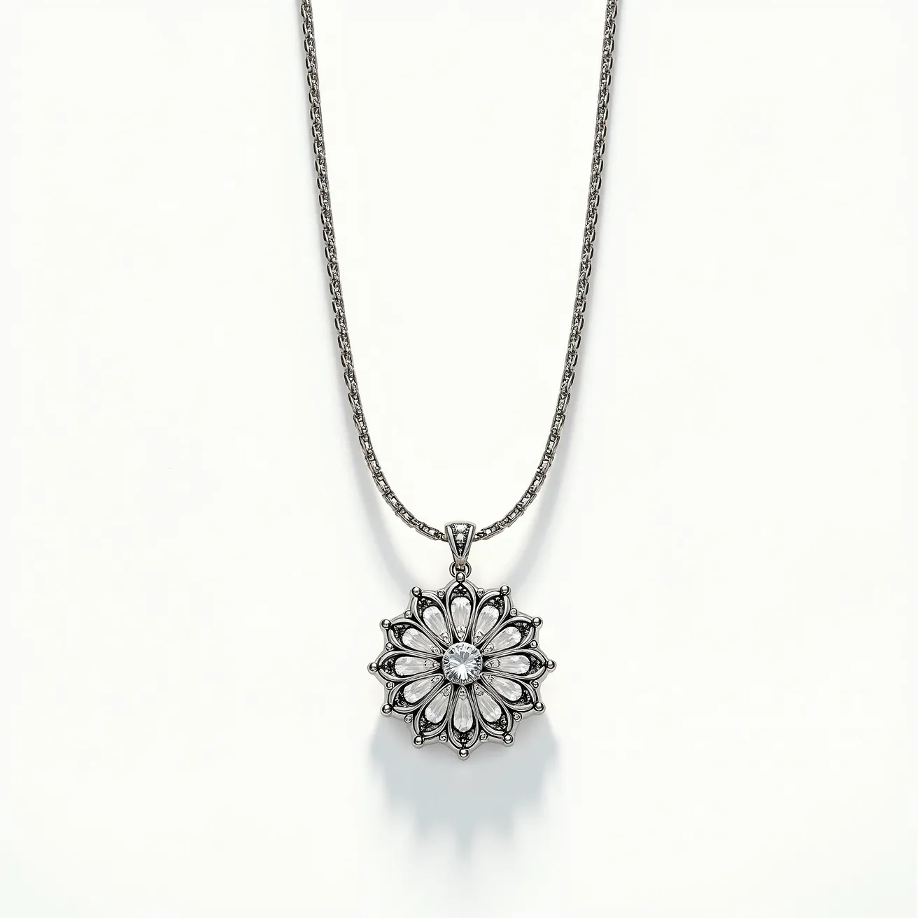 This pendant necklace features a striking floral design with a central round-cut gemstone, likely a diamond or cubic zirconia, set in a metal frame that appears to be silver or white gold. The pendant is crafted with intricate petal-like structures surrounding the central stone, each resembling a teardrop shape, possibly mimicking smaller gemstones or detailed metalwork. The necklace chain is a delicate design, possibly a rope or wheat style, providing an elegant accompaniment to the pendant. The pendant is attached to the chain via a simple bail, ensuring the focus remains on the intricate design of the pendant itself.