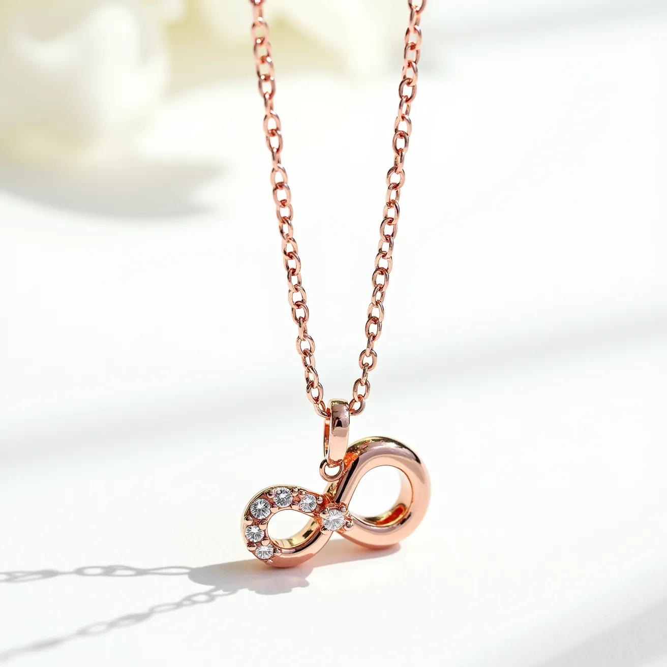 This pendant necklace features an infinity symbol crafted in rose gold, highlighted with a series of small round-cut diamonds. The gems are elegantly set on one side of the pendant, enhancing its luxurious appeal. The chain itself is composed of rose gold links that complement the pendant's design. The necklace is secured with a simple clasp, ensuring ease of wear and a secure fit.