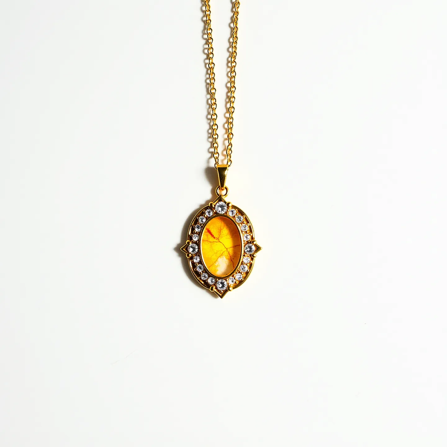 This pendant necklace features an elegant oval-shaped design with a warm orange gemstone at its center. The centerpiece is highlighted by a gold-toned setting, which adds a touch of classic sophistication. Encircling the central stone, there is a series of round, clear stones that resemble diamonds, each securely placed in a symmetrical pattern, enhancing the pendant's visual appeal. The pendant is suspended from a delicate gold-toned chain that complements the overall design. The attachment is a simple, yet effective bail that seamlessly integrates with the necklace's aesthetic, ensuring the pendant hangs beautifully when worn.