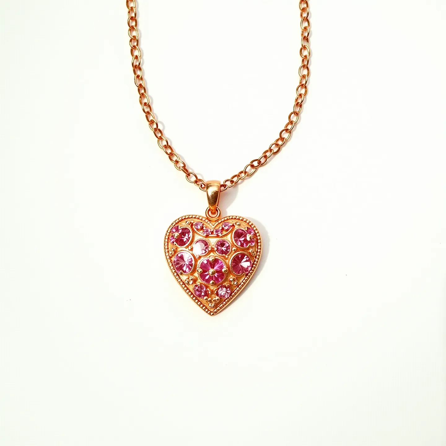 This pink heart necklace features a heart-shaped pendant adorned with multiple pink gemstones, possibly zircon or cubic zirconia, each cut in a round brilliant style to enhance their sparkle. The stones are prong-set within the pendant, which appears to be crafted from a polished, gold-toned metal, adding warmth and contrast to the vibrant pink stones. The pendant is attached to a matching gold-toned chain, consisting of uniform oval links. The chain is secured with a classic lobster clasp, providing a reliable and easy-to-use closure.