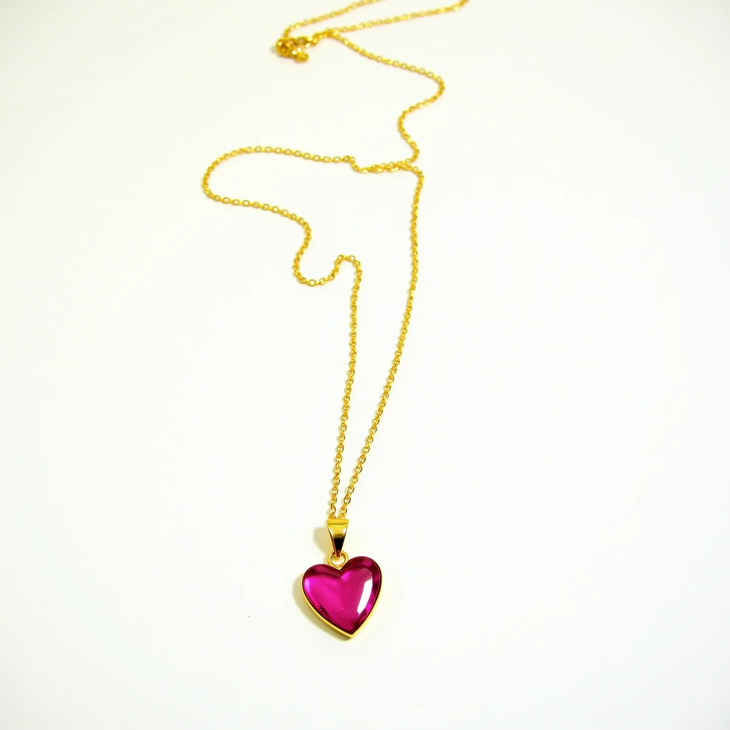 This pink heart necklace features a vibrant heart-shaped gem, likely a pink crystal or glass, which is smoothly cabochon-cut to enhance its glossy appearance. The gem is set in a polished gold-colored metal frame that complements its vivid hue perfectly. Hanging from a delicate gold-colored chain, the pendant is secured with a simple bail that allows it to dangle freely. The chain likely has a standard clasp for easy fastening, matching the overall elegant design.