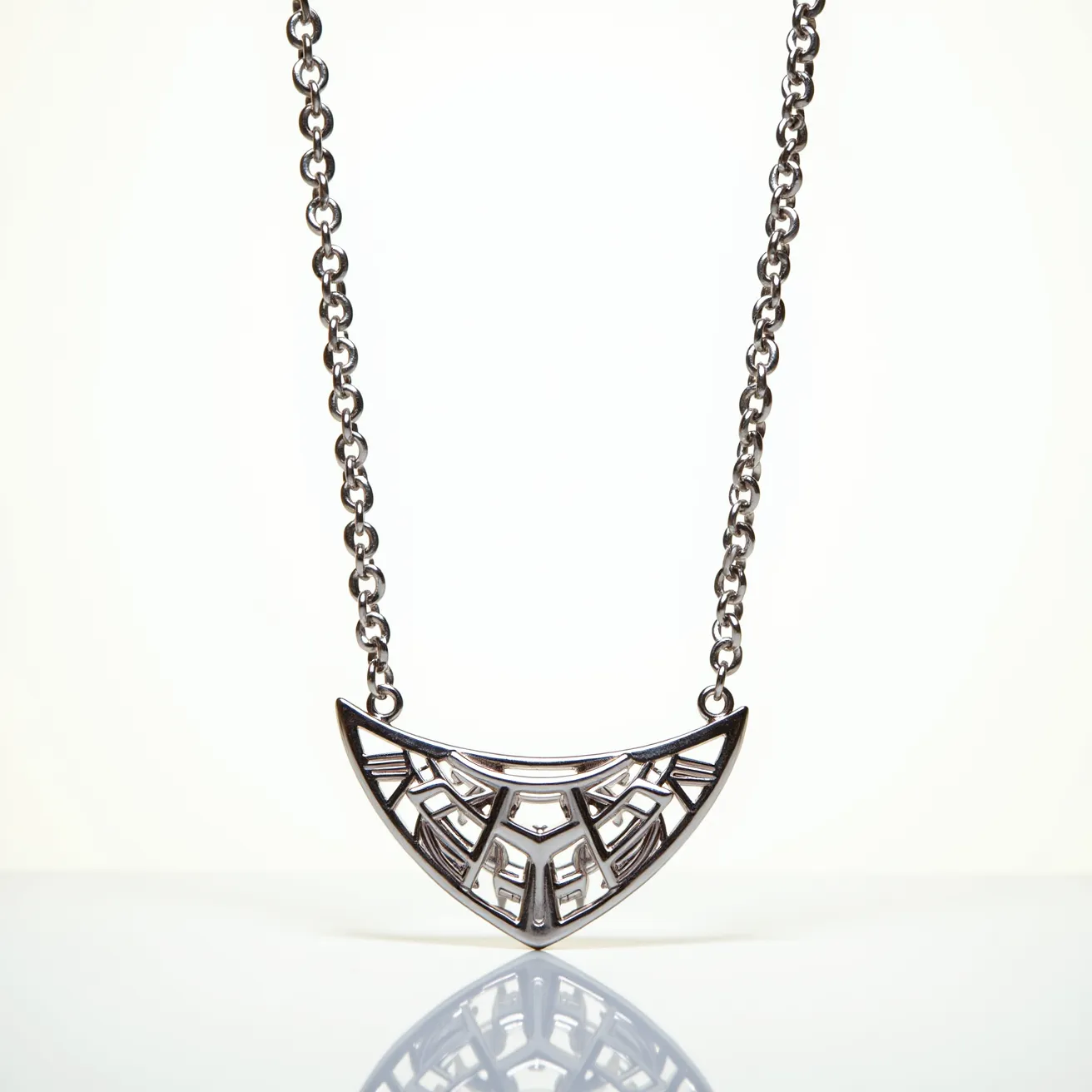 This platinum necklace features a bold, geometric pendant in the shape of a crescent, intricately designed with carefully crafted patterns reminiscent of architectural motifs. The pendant is composed solely of platinum, showcasing its sleek and polished finish. The necklace is attached to a sturdy chain characterized by uniform, interlocking links that complement the pendant's design. Each detail is executed with precision, creating a cohesive and elegant piece. The necklace secures with a standard clasp, ensuring both ease of wear and security.