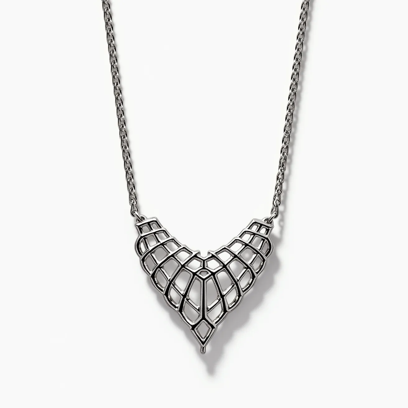 This platinum necklace features an intricate, lattice-like pendant design, showcasing a geometric, webbed pattern that adds a modern, architectural appeal. The necklace comprises a closely linked platinum chain that provides both durability and a subtle elegance, complementing the bold central piece. The distinct V-shaped pendant is crafted entirely from platinum, emphasizing the luxurious sheen and timeless quality of the material. The necklace likely includes a secure clasp mechanism, typical of fine jewelry, ensuring easy wearability and safety when worn. Overall, this finely detailed piece exemplifies sophisticated design and craftsmanship.