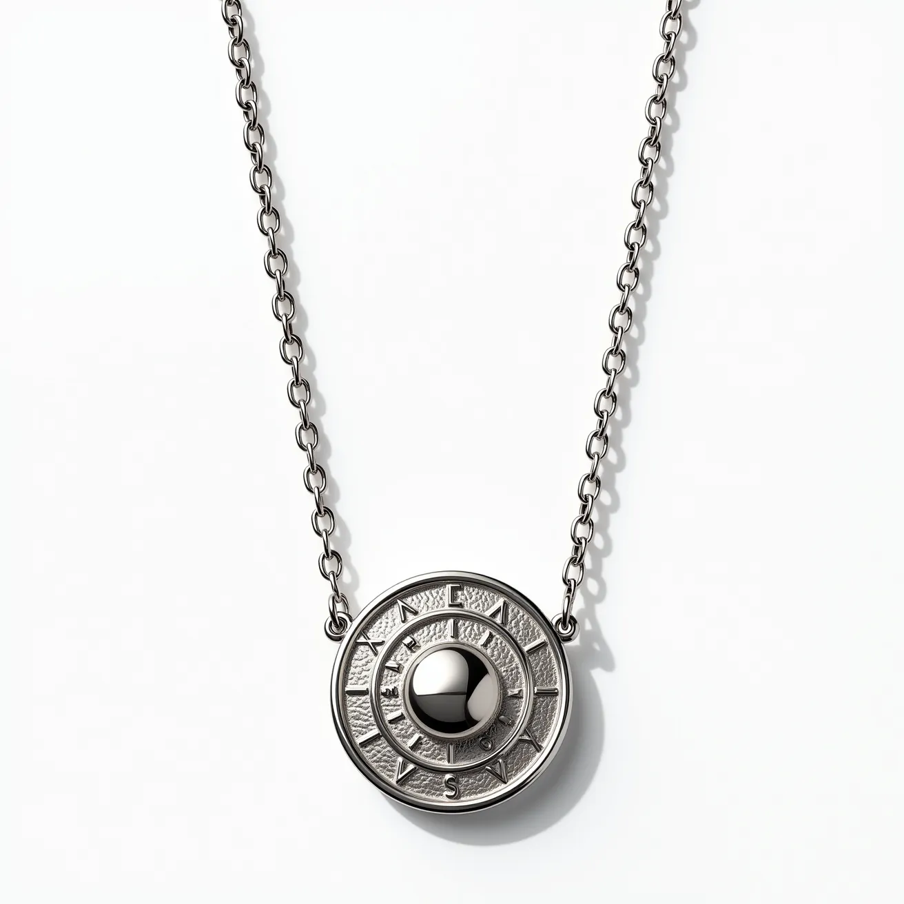 This platinum necklace features a circular pendant with a striking design that incorporates both texture and smooth finishes. At its center is a polished sphere that adds a modern touch to the piece. The surrounding area is intricately carved, featuring a series of concentric circles and engraved patterns that resemble celestial symbols or lettering, creating an elegant and sophisticated look. The necklace is held together by a sturdy chain with oval links that provide durability and a classic appearance. The pendant is securely attached to the chain through two loops on either side, ensuring it hangs evenly and securely.