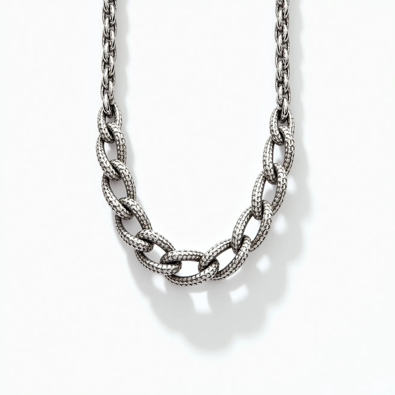 This platinum necklace features a series of intricately textured, interlocking links that create a bold and elegant chain design. The links are crafted entirely from platinum, showcasing the metal's signature silvery luster. Each link is uniformly textured, adding depth and interest to the overall piece. The necklace appears to utilize a classic lobster clasp, ensuring a secure and durable fastening. Its design presents a modern yet timeless aesthetic, making it versatile for various occasions.