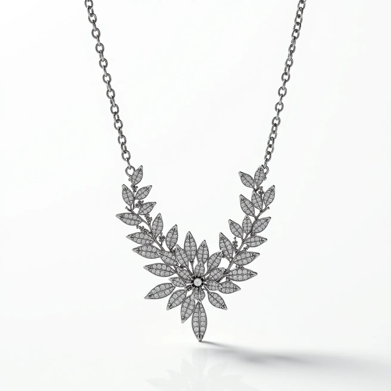 This platinum necklace features an intricate floral design, with leaves and petals adorned with numerous small round-cut diamonds securely set in a pavé setting. The central element of the design extends outward with a symmetrical arrangement, highlighting a larger diamond at the center of the flower. The necklace is attached to a fine chain, which is made of platinum links, adding to its elegance and cohesion. The overall craftsmanship showcases a harmonious blend of classic elegance and refined detail, making it a statement piece.