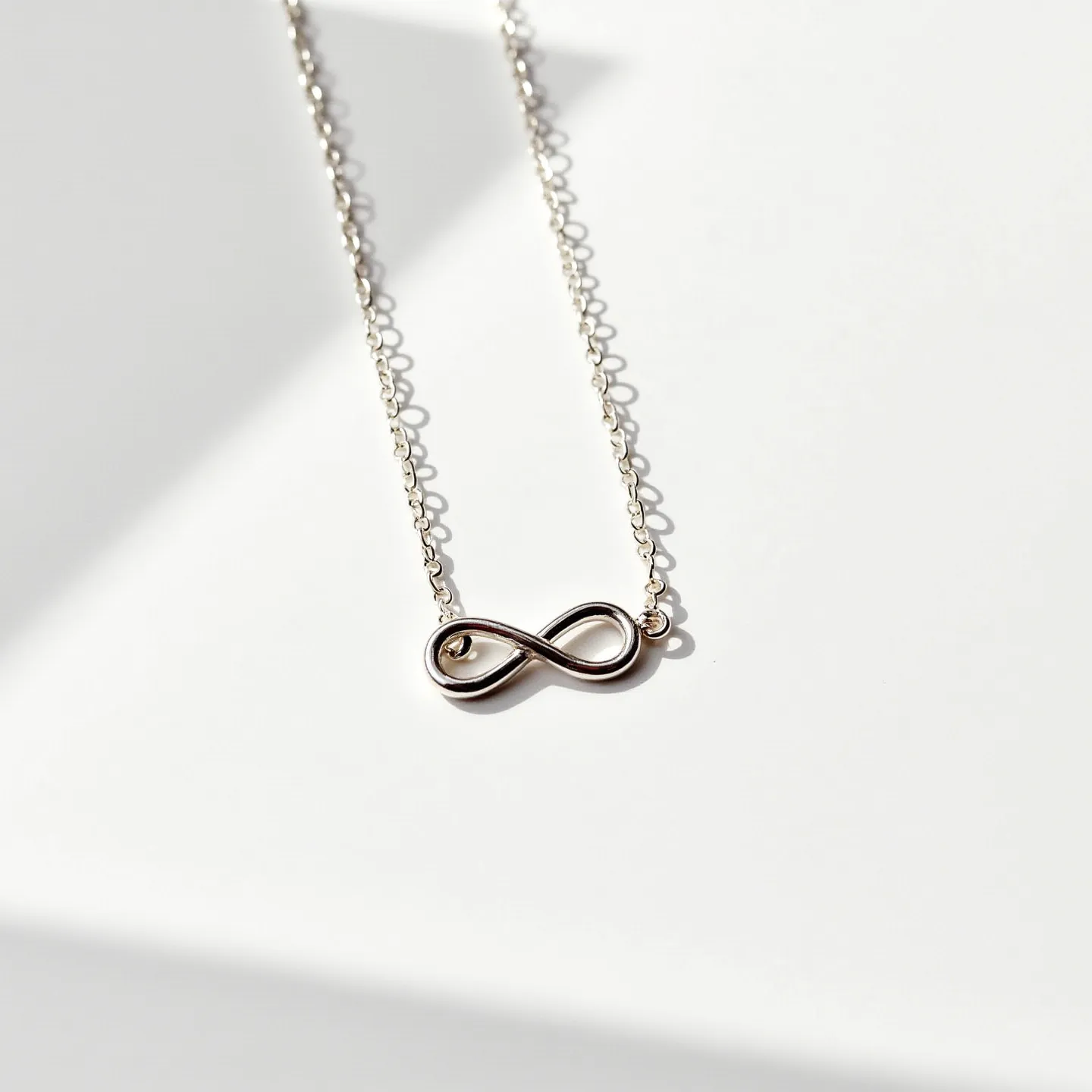 This promise necklace features a delicate chain made of a light metal, likely silver or a similar alloy, which provides a subtle and elegant backdrop to its central motif. The pendant is an infinity symbol, seamlessly integrated with the chain, signifying endless commitment and timelessness. The infinity symbol is crafted from the same material as the chain, contributing to a cohesive and polished look. The necklace is secured with a standard spring ring clasp, ensuring both functionality and simplicity.