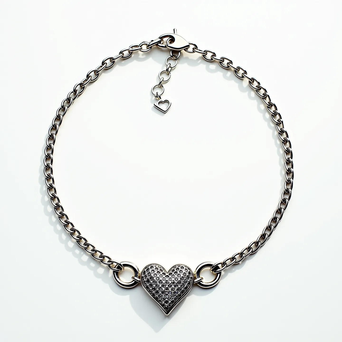 This promise necklace features a sterling silver chain with a central heart-shaped pendant. The heart is embellished with a cluster of round-cut stones that are closely set, creating a pavé effect that adds a touch of sparkle. The necklace is secured with a lobster clasp, which provides a reliable closure, and has an adjustable extension chain with a small heart charm at the end, allowing for length customization. The overall design combines elegance with sentimentality, making it a meaningful piece of jewelry.