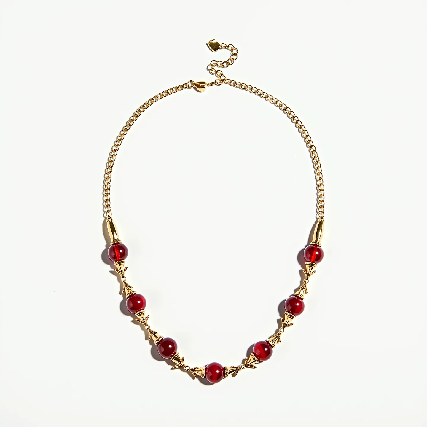 This red necklace features vibrant round beads that appear to be made of a polished red stone, possibly red agate or glass. The beads are uniformly spherical and are spaced evenly along the necklace. Each bead is separated by intricate gold-toned metalwork, which adds a decorative and ornate element to the piece, giving it a classic and elegant appearance. The necklace is completed with a gold-toned chain, offering a sleek and complementary background to the bold red beads. The piece includes a lobster clasp with an adjustable chain, providing ease of wear and allowing for length customization to suit different styles or preferences.