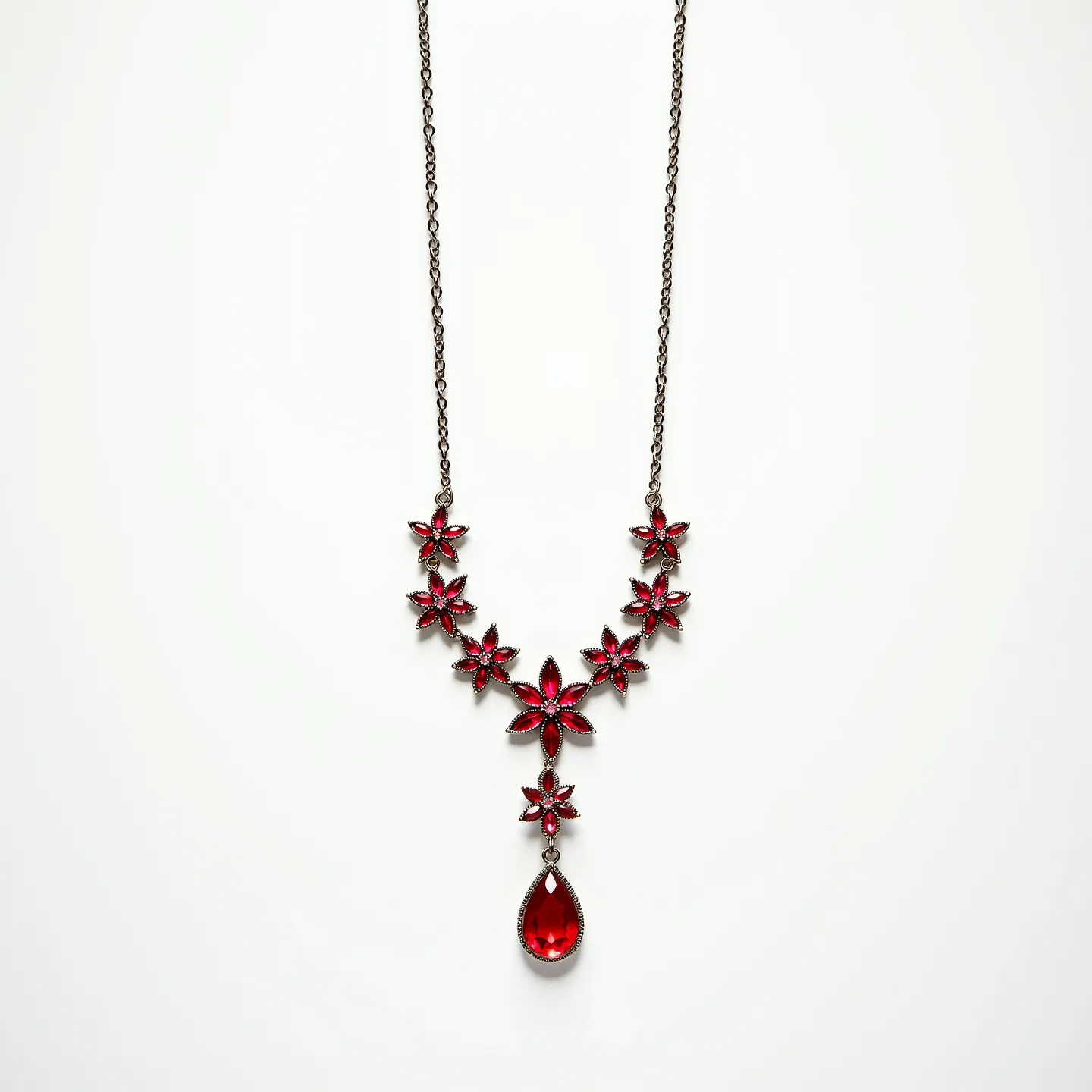 This red necklace features a series of intricately designed metal floral motifs, each adorned with vibrant red stones resembling gemstones. The focal point is a teardrop-shaped red stone, prominently set in a bezel-style setting, which hangs elegantly from the central floral motif. Each floral element is composed of marquise-cut stones radiating from the center, creating a petal-like appearance. The necklace is connected by a delicate chain that complements the ornate design of the centerpiece. This piece is secured with a classic lobster clasp, ensuring easy wearability while maintaining a secure fit around the neck.