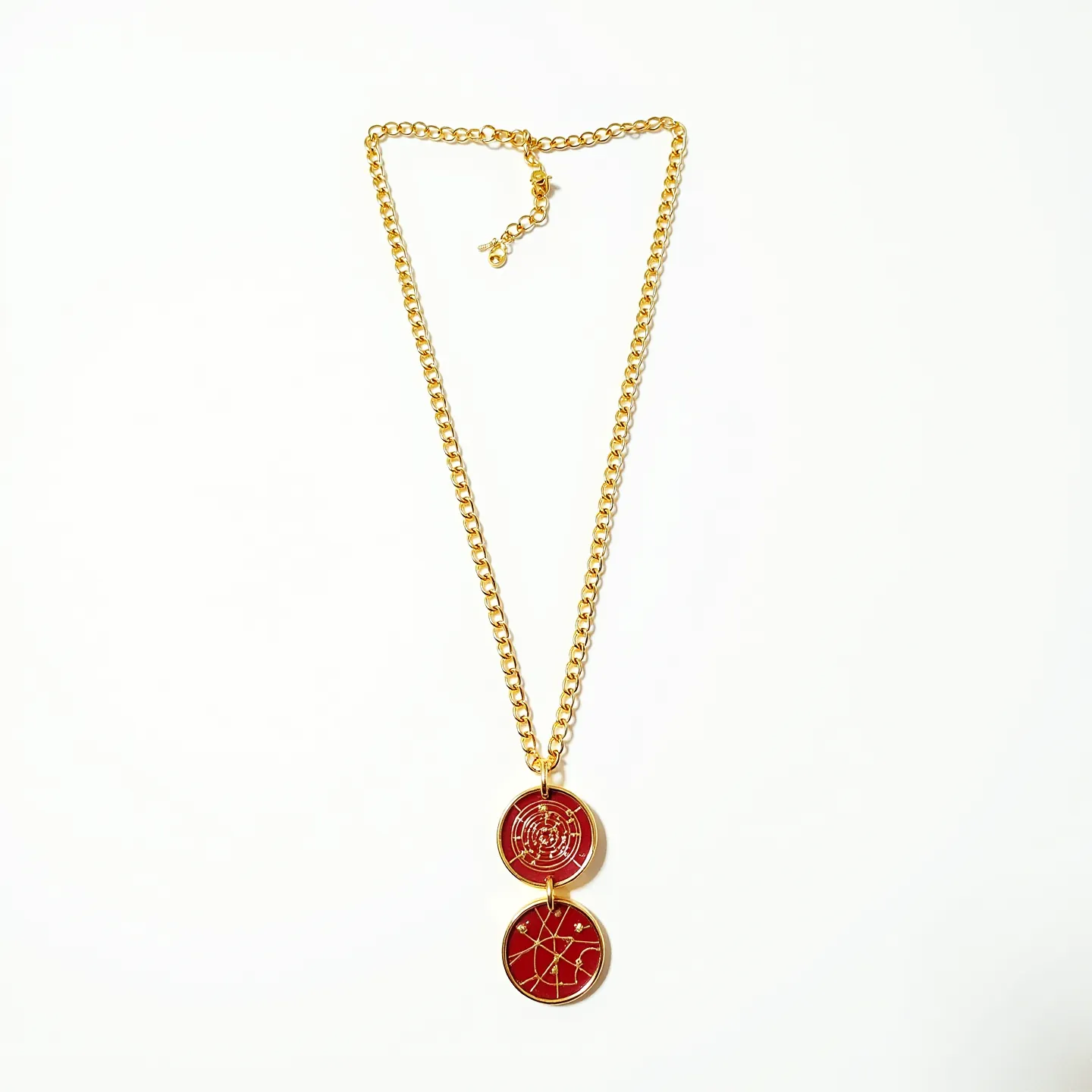 This red necklace features a striking design with two round pendants. The pendants are embedded with red enamel and adorned with intricate gold detailing, suggesting a celestial or astrological theme. The necklace is composed of a gold-toned chain, adding a touch of elegance to the piece. A lobster clasp ensures secure fastening, and an adjustable chain allows for versatile length options. The craftsmanship of the detailed settings within the pendants enhances the overall aesthetic appeal of this eye-catching accessory.