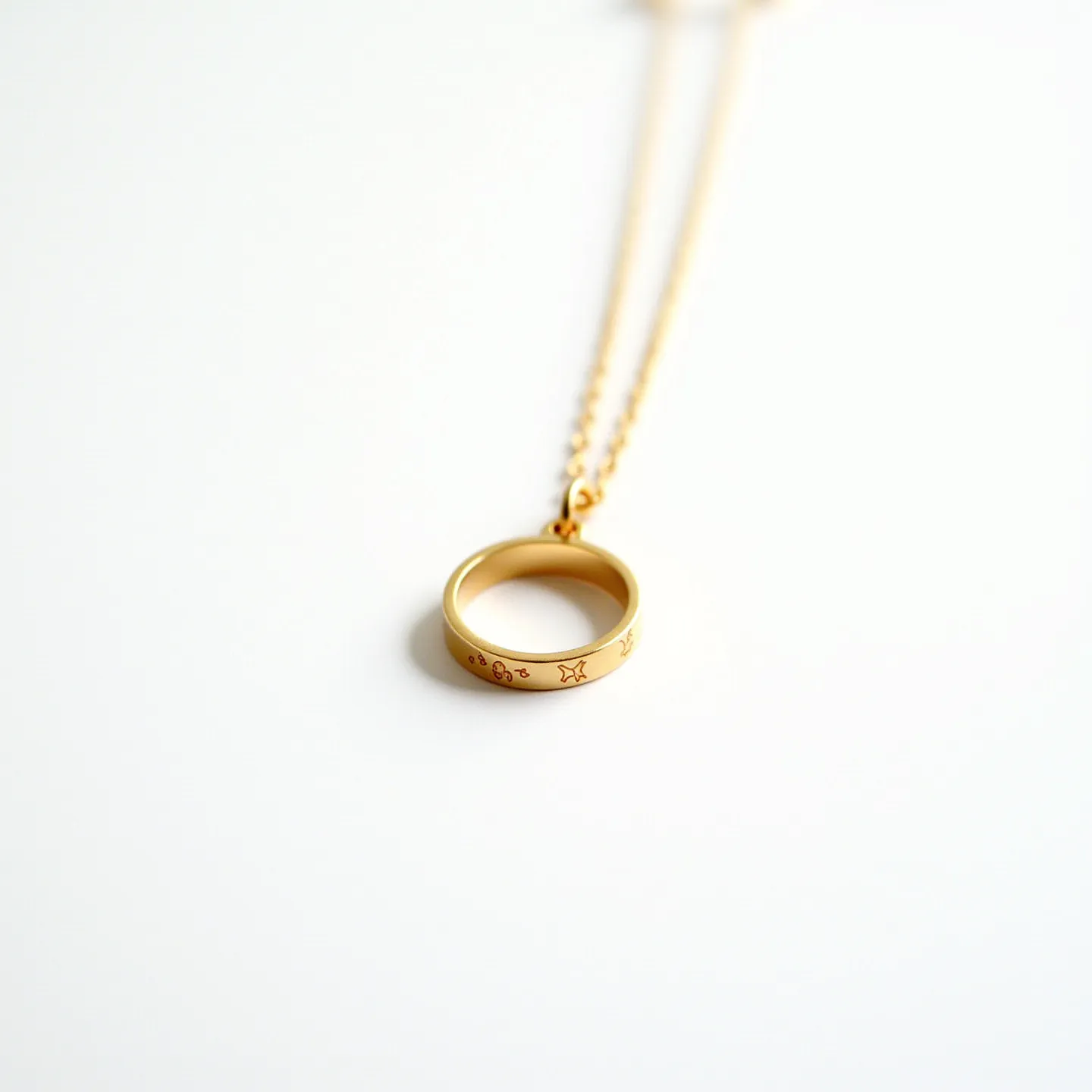 This ring necklace features a simple yet elegant design, with a gold ring that serves as the pendant. The ring is adorned with small engraved symbols, adding a touch of detail and personalization. It hangs from a delicate gold chain, which is likely made of the same material as the ring, creating a harmonious and cohesive look. The attachment is simple, allowing the ring to move freely along the chain. The overall design is understated yet stylish, making it suitable for everyday wear or special occasions.