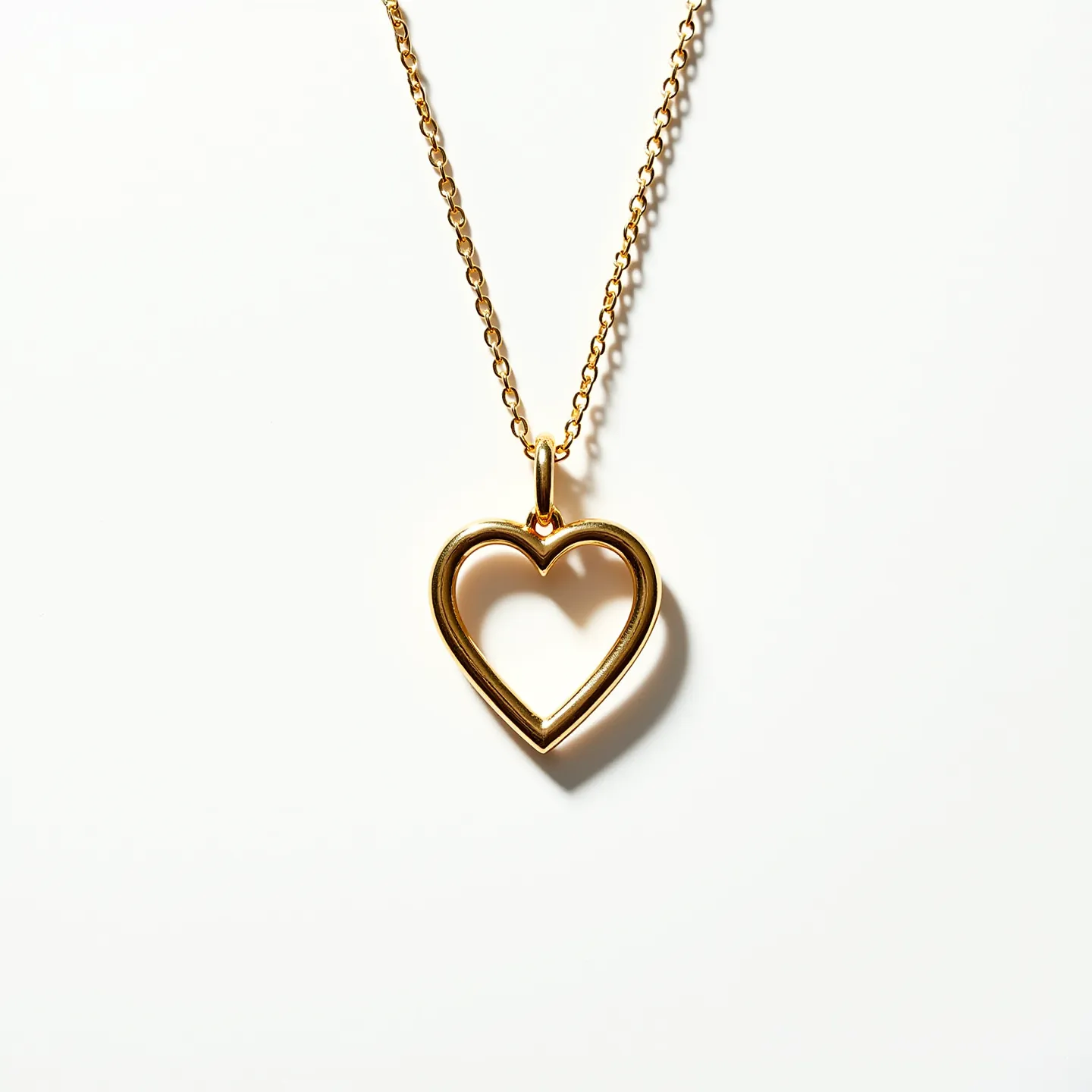 This ring necklace features a delicate gold-tone chain and a heart-shaped pendant. The pendant has a smooth, polished finish, creating a sleek and elegant look. The gold chain appears to be finely linked, enhancing the overall sophistication of the piece. The necklace is equipped with a simple loop for attaching the pendant to the chain, allowing the heart to hang freely. The absence of gems or stones gives it a minimalist and timeless appeal, making it suitable for various occasions. The clasp is a standard lobster clasp, providing both security and ease of use.