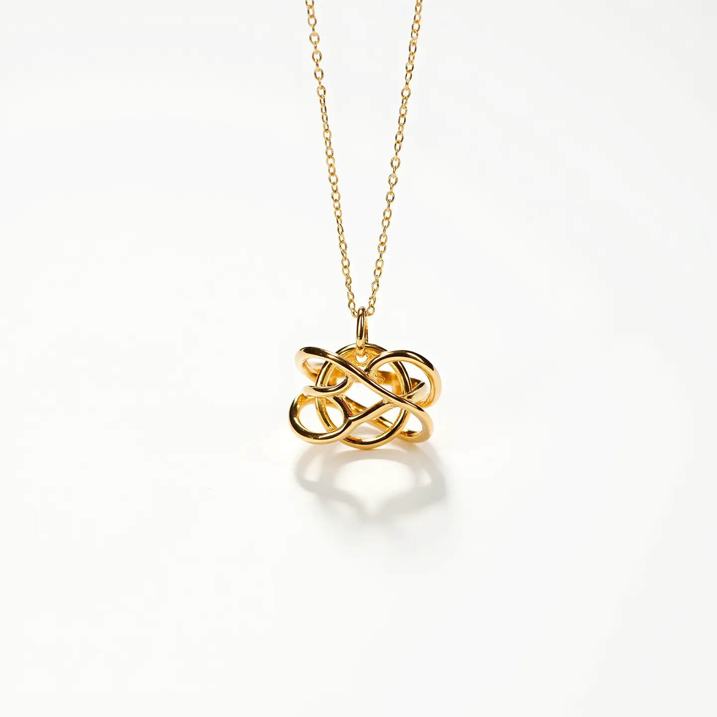 This ring necklace features a gold-hued pendant crafted in an interwoven loop design, reminiscent of an intricate knot, suspended from a delicate chain. The chain is likely made of gold or a gold-plated material, complementing the pendant's sheen. The pendant does not appear to contain any gemstones, maintaining a sleek and modern look. The chain is thin and appears to close with a simple clasp, ensuring a secure attachment while maintaining elegance and minimalism.