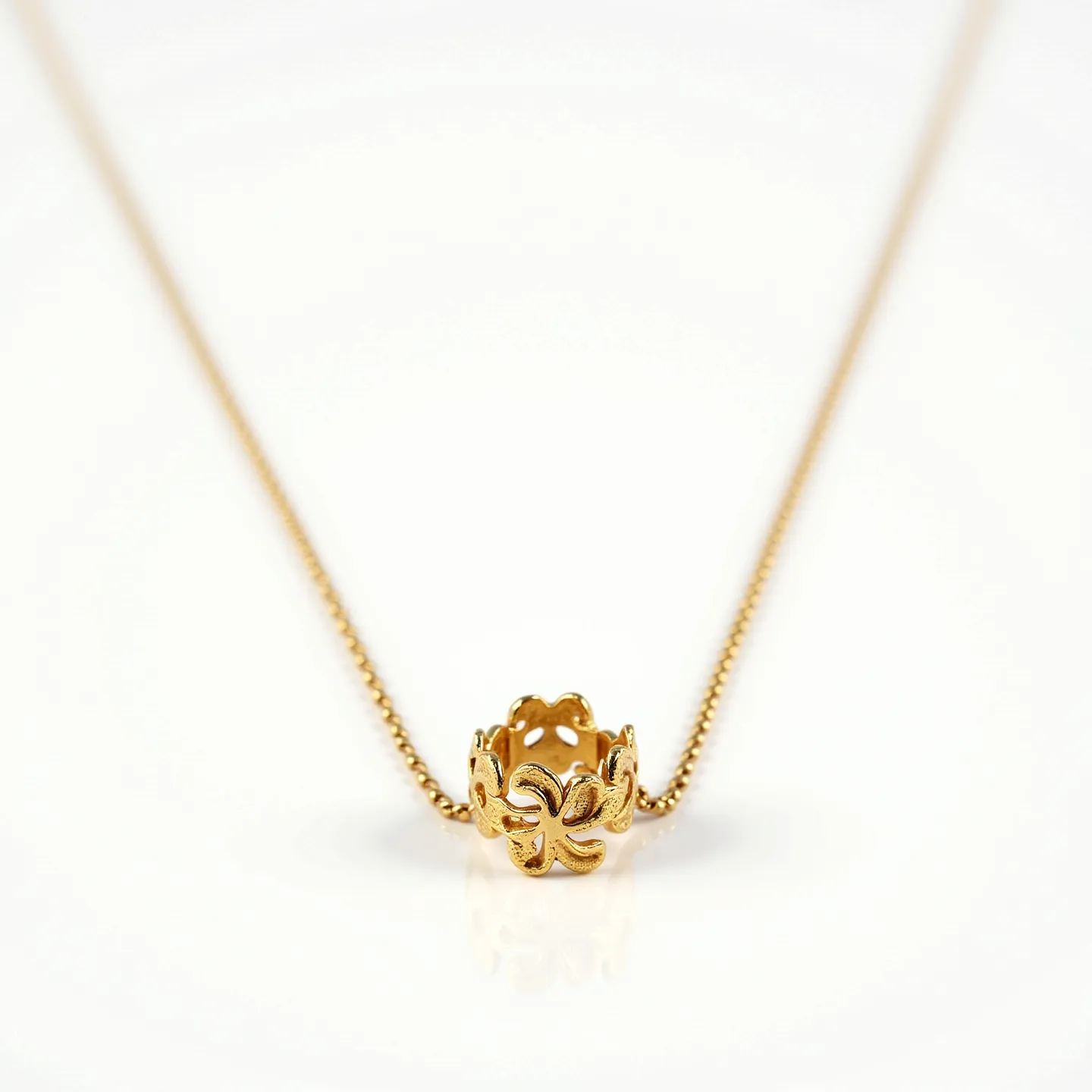 This ring necklace features an intricately designed ring pendant crafted from what appears to be gold, showcasing a floral or organic pattern that is both elegant and eye-catching. The pendant hangs from a delicate, finely linked chain that is likely gold or gold-toned, complementing the pendant's material. The floral design of the ring suggests a sophisticated craftsmanship, enhancing its aesthetic appeal. There are no visible gems or stones on the pendant. The chain likely uses a standard clasp mechanism, typical for necklaces of this design, ensuring a secure fit.