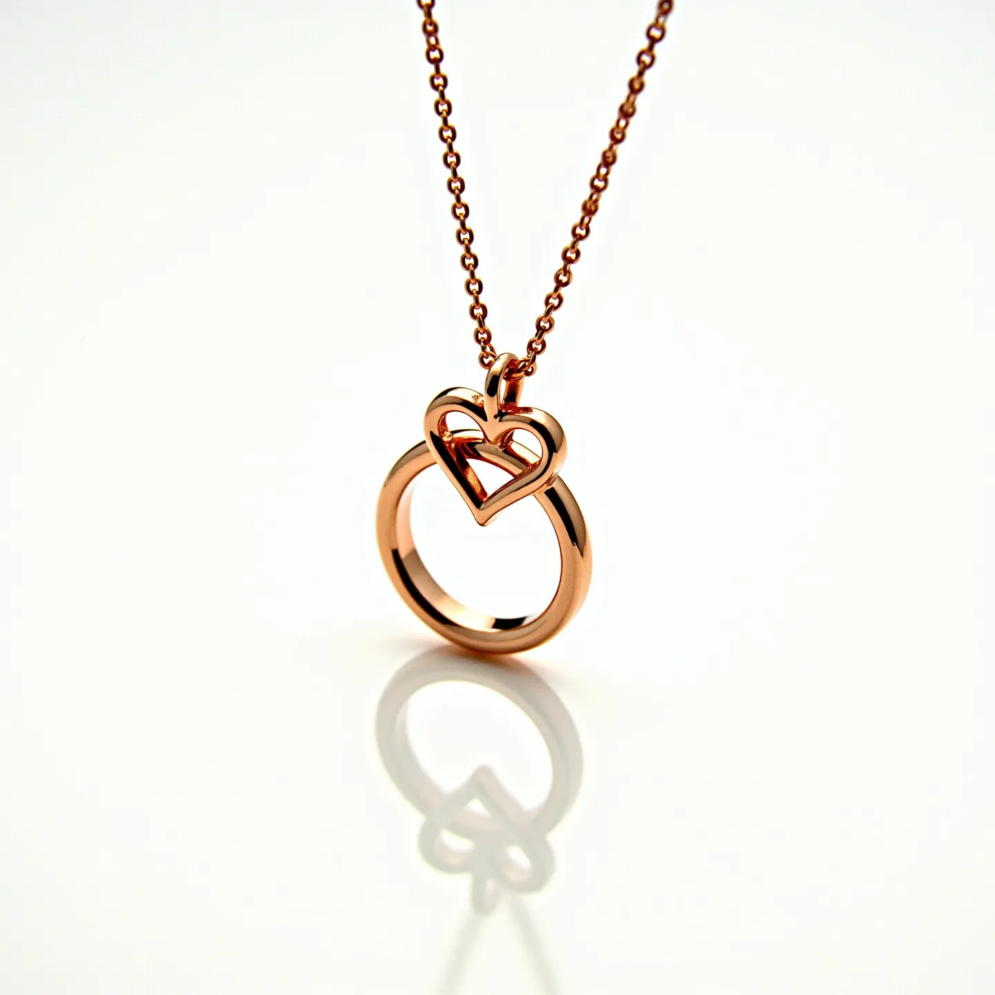 This ring necklace features a rose gold-colored metal in a circular ring design, accompanied by an open heart motif intertwined with the ring. The chain is composed of small, uniform links that complement the pendant's simplicity. The necklace does not display any visible gemstones, focusing on the smooth, polished appearance of the metal. The attachment method appears to be a standard chain passing through the pendant arrangement, ensuring secure wear and aesthetic flow.