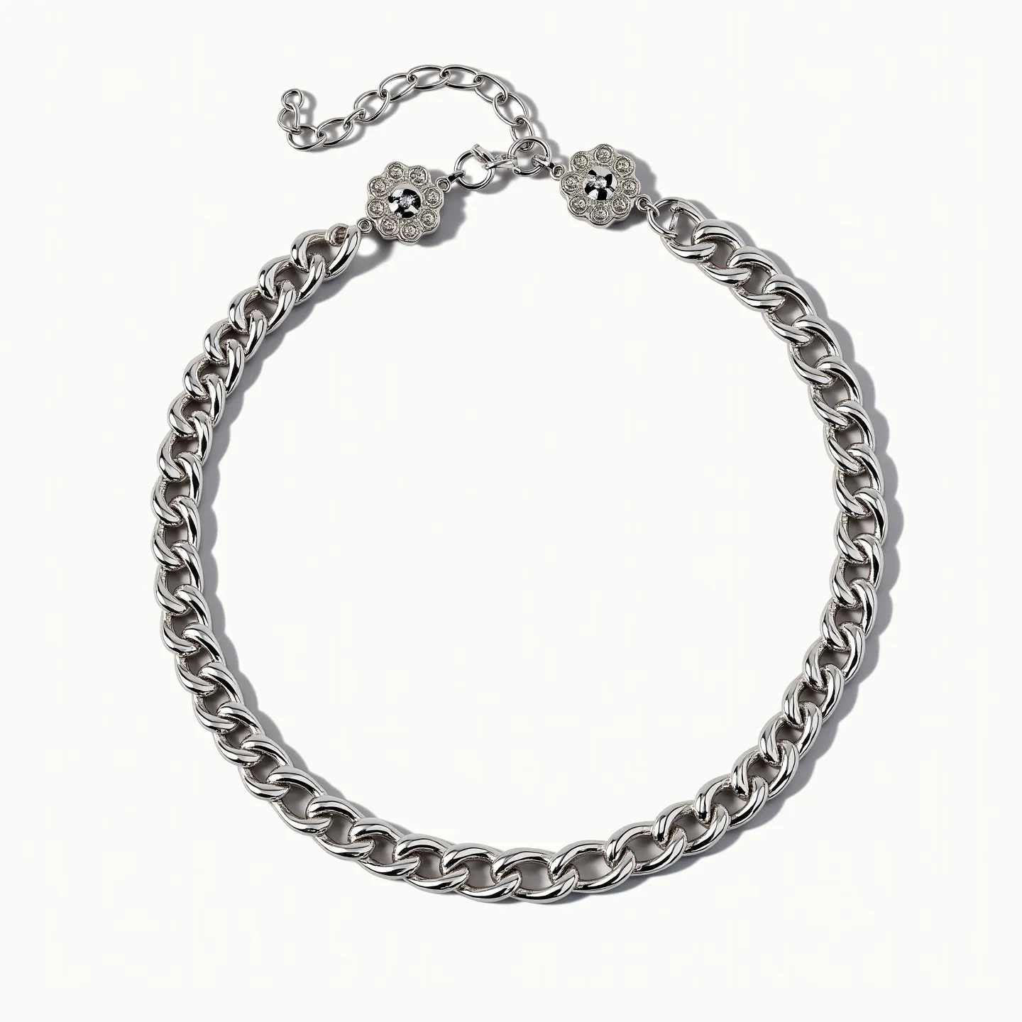 This rolo chain necklace is crafted from a sleek, polished metal, giving it a modern and sophisticated appearance. The chain is composed of uniform, circular links that create a smooth and consistent pattern throughout. The necklace features two floral embellishments, each set with a central round black stone, contributing a captivating contrast to the metallic sheen of the chain. These stones are set in a decorative, bead-like setting, enhancing the necklace's intricate design. The clasp is an adjustable hook style, allowing for customization in length, and is accompanied by a short chain extension for added flexibility.