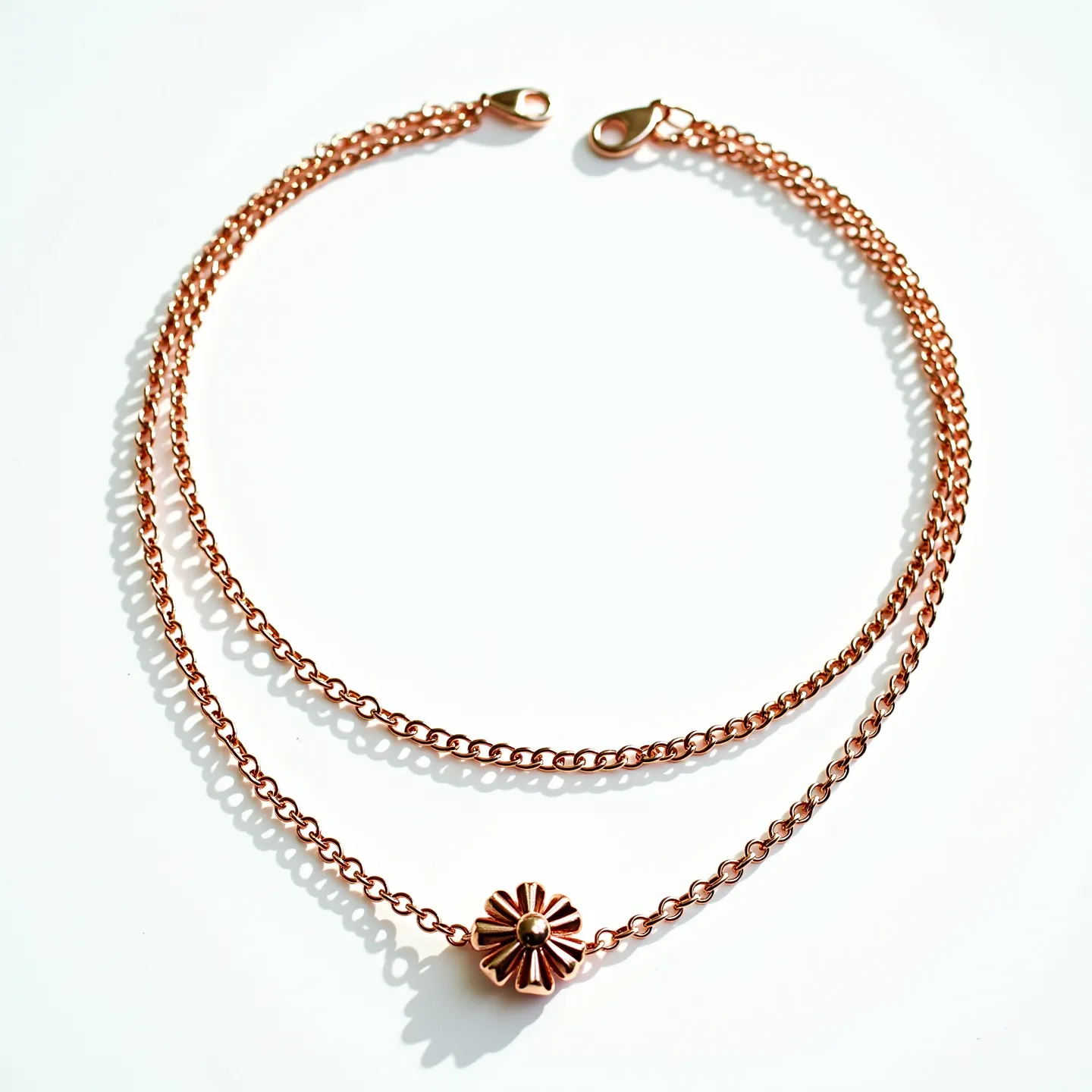 This rolo chain necklace is designed with a warm rose gold finish, featuring round links that provide a classic and elegant appearance. At its center, it holds a floral-inspired charm, characterized by petal-like extensions and a central round bead, adding a touch of decorative interest. The necklace is secured with a lobster clasp, which offers a convenient and reliable fastening method. The combination of its minimalist chain design with the unique central charm makes it versatile for various occasions.