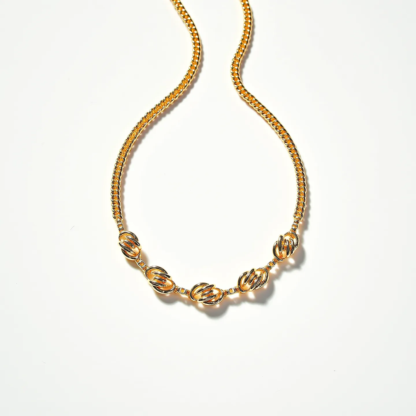 This rolo chain necklace features a series of interconnected round links, crafted from gold-toned metal, creating a classic and elegant appearance. The design incorporates several spherical elements that seem intricately twisted, adding a decorative touch to the otherwise simple chain. These spheres appear to be hollow, amplifying their visual appeal without adding much weight. The necklace does not prominently display any gemstones, focusing instead on the brilliance of the metal itself. The necklace includes a discrete clasp that complements the overall aesthetic and ensures a secure fit, making it both fashionable and functional.