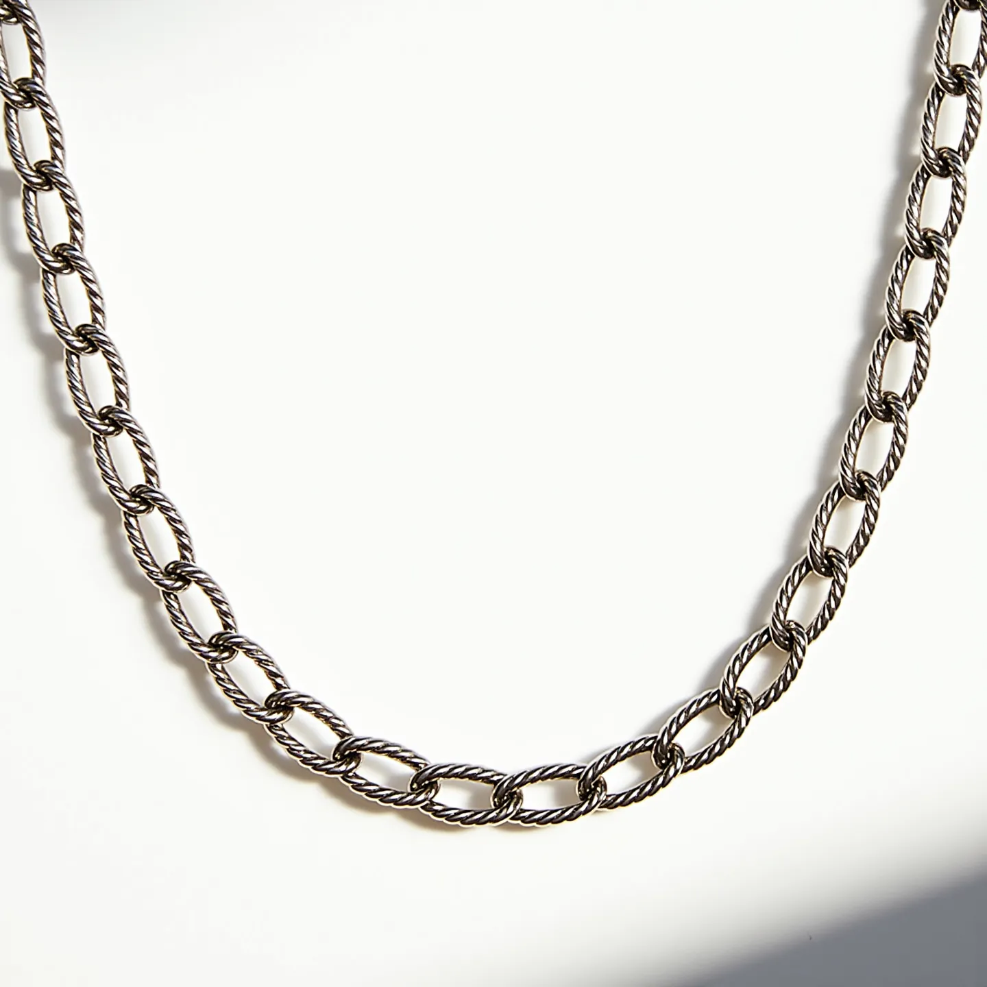 This rope chain features a series of twisted, metallic links, creating a texture that mimics the appearance of intertwined strands. The metal exhibits a silver hue, suggesting it could be crafted from a material like sterling silver or stainless steel, offering both durability and a sleek finish. The links are uniform in size and are connected seamlessly, allowing for smooth and comfortable wear. The absence of stones or additional adornments highlights the chain's elegance and simplicity, making it versatile for everyday wear. It likely incorporates a standard clasp mechanism at the ends, facilitating easy fastening and removal.