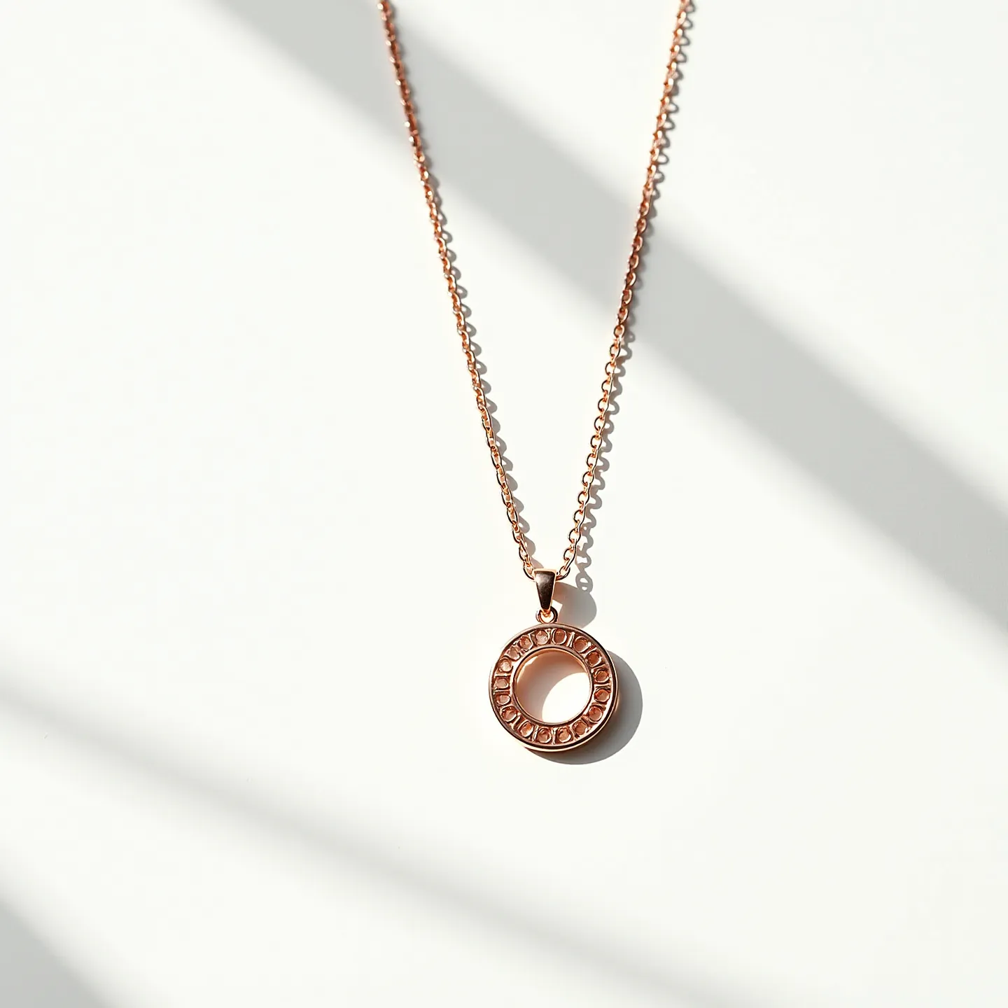 This rose gold necklace features a delicate chain that elegantly supports a circular pendant. The pendant is crafted from rose gold, enhancing its warm, pinkish hue. Encircling the pendant is a series of small, intricately set stones that catch and reflect light, adding a hint of sparkle. The pendant is attached to the chain with a simple, seamless bail that maintains the necklace’s minimalist yet stylish design. A conventional spring ring clasp ensures the necklace is easy to fasten and secure when worn.