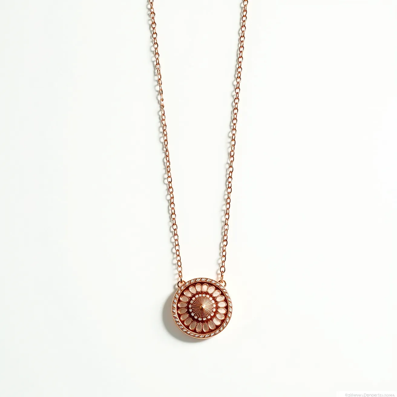 This rose gold necklace features a delicate chain that supports an intricate circular pendant. The pendant design resembles a floral pattern with an ornate, symmetrical arrangement that gives it an eye-catching detail. The center of the pendant has a small, dome-like embellishment that adds to its elegance. The necklace appears to have a lobster clasp, which is a common and secure type of closure for ease of wear. Overall, the necklace exudes a balanced blend of simplicity and sophistication, perfect for adding a touch of elegance to any outfit.