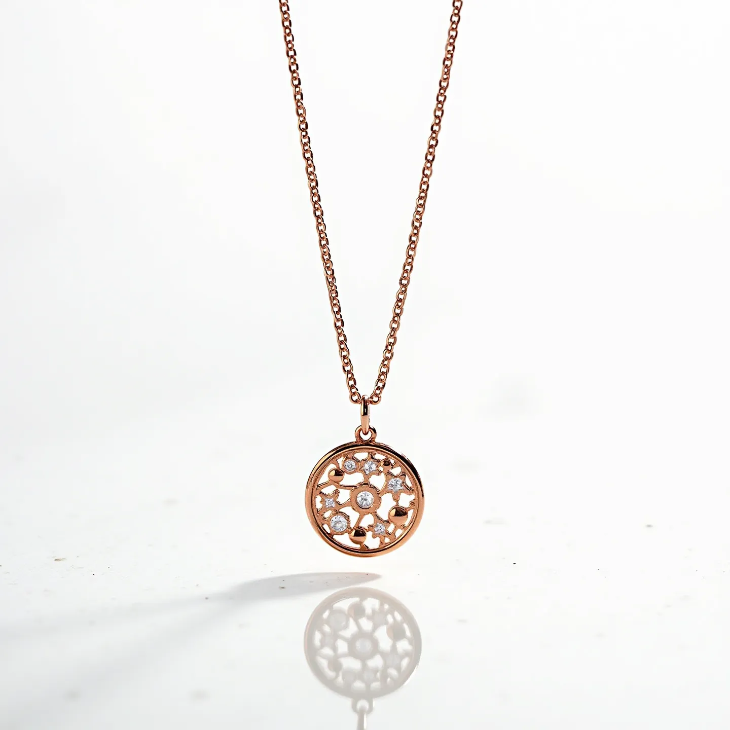 This rose gold necklace features a delicate chain complemented by a circular pendant adorned with small, sparkling gems. The stones, likely diamonds, are set within an intricate floral-inspired design that exhibits a halo effect. The pendant's detailed arrangement enhances the necklace's elegance, showcasing the exquisite craftsmanship. The chain is secured with a classic spring ring clasp, ensuring both style and functionality in its design.