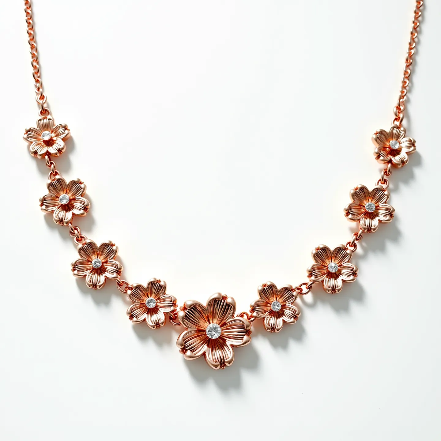 This rose gold necklace features intricately designed floral motifs, each adorned with a central gem that resembles a round brilliant cut, likely a diamond or diamond-like stone. The petals are crafted with detailed grooves that catch and reflect light, enhancing the necklace's elegance. The flowers are linked together with a delicate rose gold chain, providing a harmonious and fluid design. The necklace includes a secure clasp that ensures it remains fastened comfortably around the neck. This sophisticated piece showcases a blend of artistry and craftsmanship, making it a versatile accessory for various occasions.