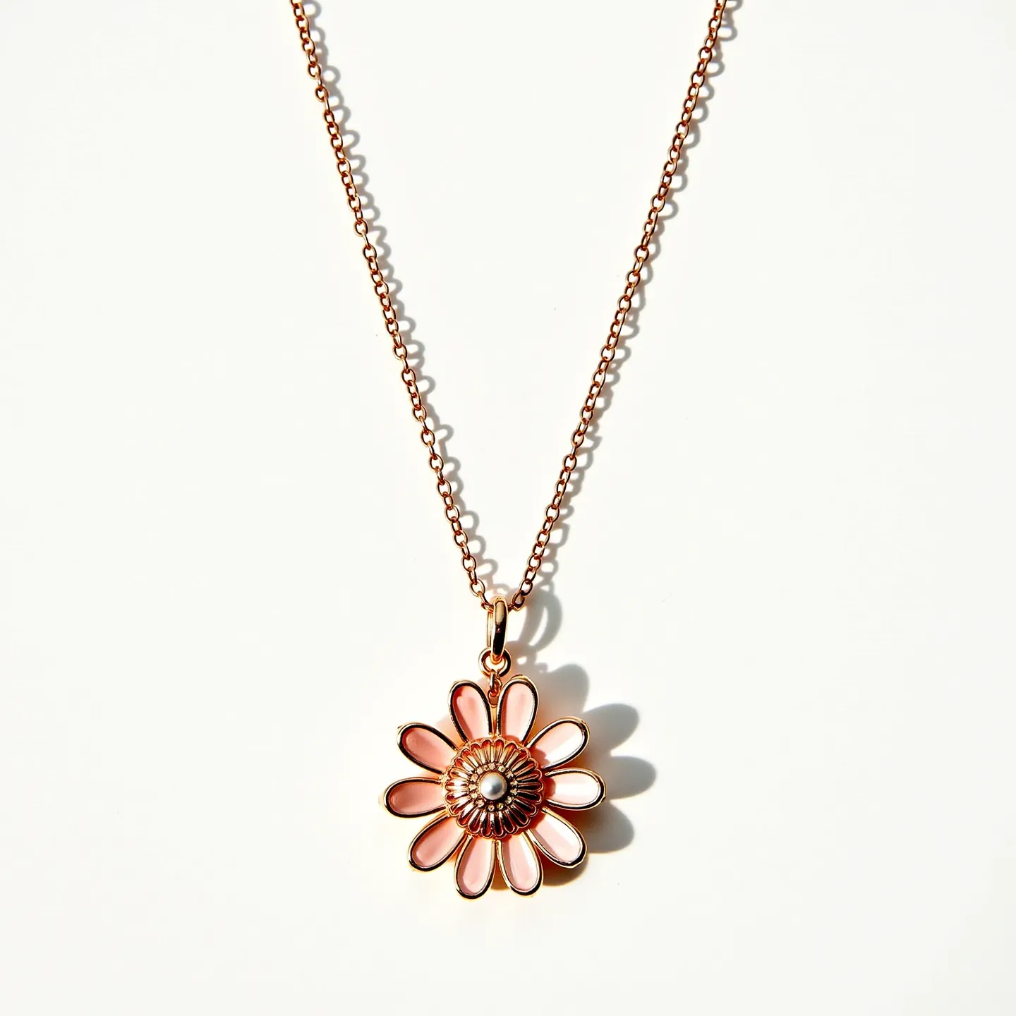 This rose gold necklace features a delicate chain that supports a flower-shaped pendant. The petals of the flower are crafted with an enamel finish, presenting subtly varied shades of pink. At the center of the floral pendant is a small pearl-like bead, which adds a touch of elegance and contrast to the design. The pendant is attached to the chain with a simple loop, allowing it to hang gracefully. The chain is composed of small, uniform links that contribute to its refined appearance, with a clasp at the back for secure fastening.