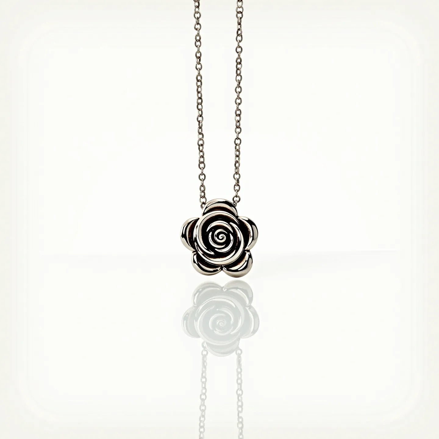 This rose necklace features a beautifully intricate rose pendant crafted from a metal that appears to have a polished, silver-like finish. The pendant captures the delicate layers and spiral design of a blooming rose, with precise detailing that highlights each petal. The necklace is attached to a simple chain that complements the elegance of the pendant. The chain appears to be a basic cable style, linking seamlessly into the pendant, ensuring fluidity in the design. The overall look is one of refined simplicity, making it versatile for various occasions.