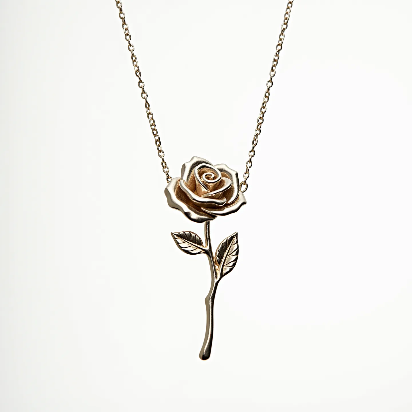 This rose necklace features a delicate metal rose pendant that captures the intricate details of a blooming flower, including its curving petals and accompanying leaves. The metallic finish suggests a gold or gold-toned material, giving it an elegant and timeless appearance. The pendant is attached to a fine chain, which complements the design without overpowering it. No additional gems or stones are set within the rose, allowing its craftsmanship to stand out. The chain is likely secured with a standard clasp, ensuring ease of wear.