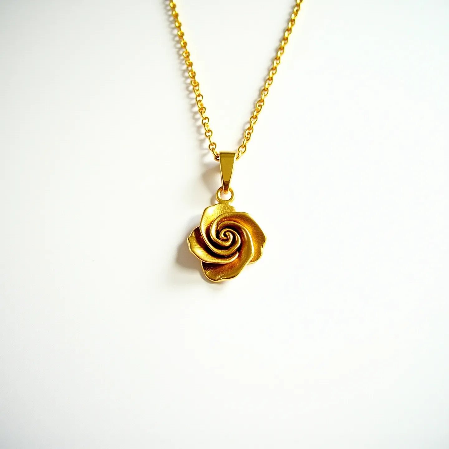 This rose necklace features a beautifully crafted rose pendant made of gold-toned metal, giving it an elegant and luxurious appearance. The pendant is designed to resemble a rose in full bloom, with intricately detailed petals creating a sense of depth and dimension. It hangs from a delicate chain also in gold-tone, which complements the pendant. The attachment between the pendant and the chain is a simple bail, enhancing the overall aesthetic without drawing attention away from the rose design. The necklace likely fastens with a standard clasp, completing its classic and sophisticated design.