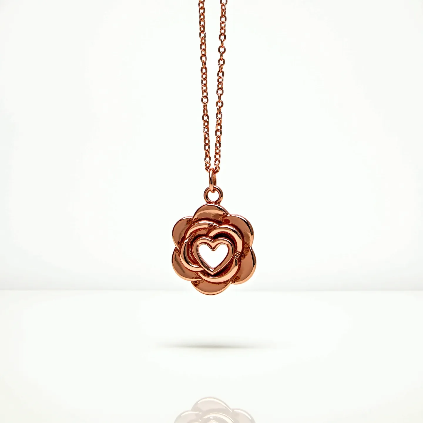 This rose necklace features a beautifully crafted rose-shaped pendant with an intricate, open-heart design at its center, all cast in a lustrous rose gold metal. The pendant hangs elegantly from a fine, matching rose gold chain, which is likely to be adjustable in length for versatile wear. The chain appears to have a simple loop clasp or similar attachment, ensuring a secure closure while maintaining the necklace's seamless aesthetic. This harmonious blend of delicate floral motifs and romantic symbolism makes it an exquisite piece for those who appreciate refined yet meaningful jewelry.